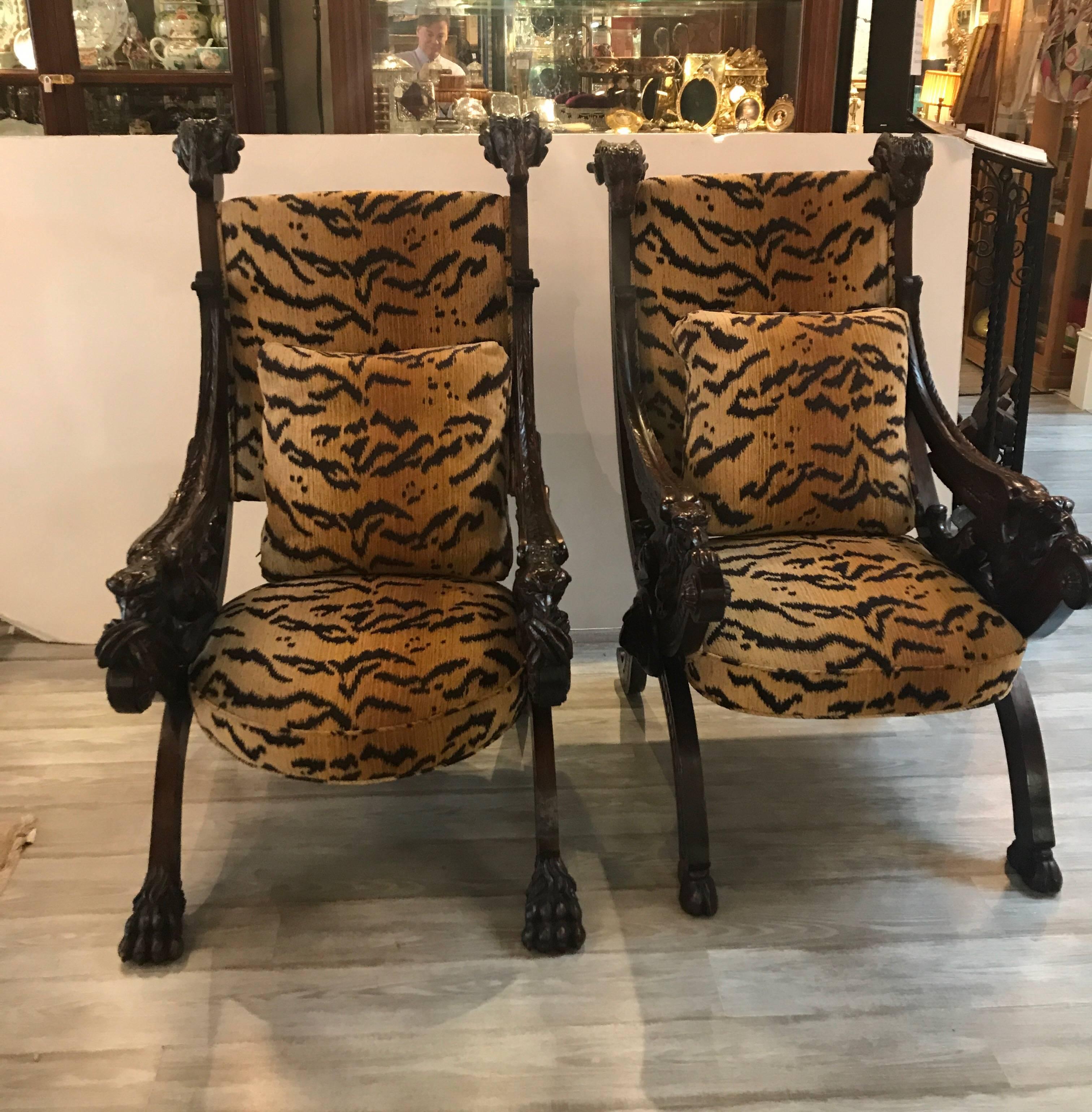 Extraordinary pair of hand carved walnut Renaissance Revival throne chairs. The heavily carved frames with winged figures of the sides, rams heads at the top and highly detailed carvings all-over. The recent fabric is a chenille in a tiger skin