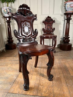 Near pair of 19th century heavily carved mahogany hall chairs