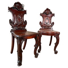 Near pair of 19th century heavily carved mahogany hall chairs