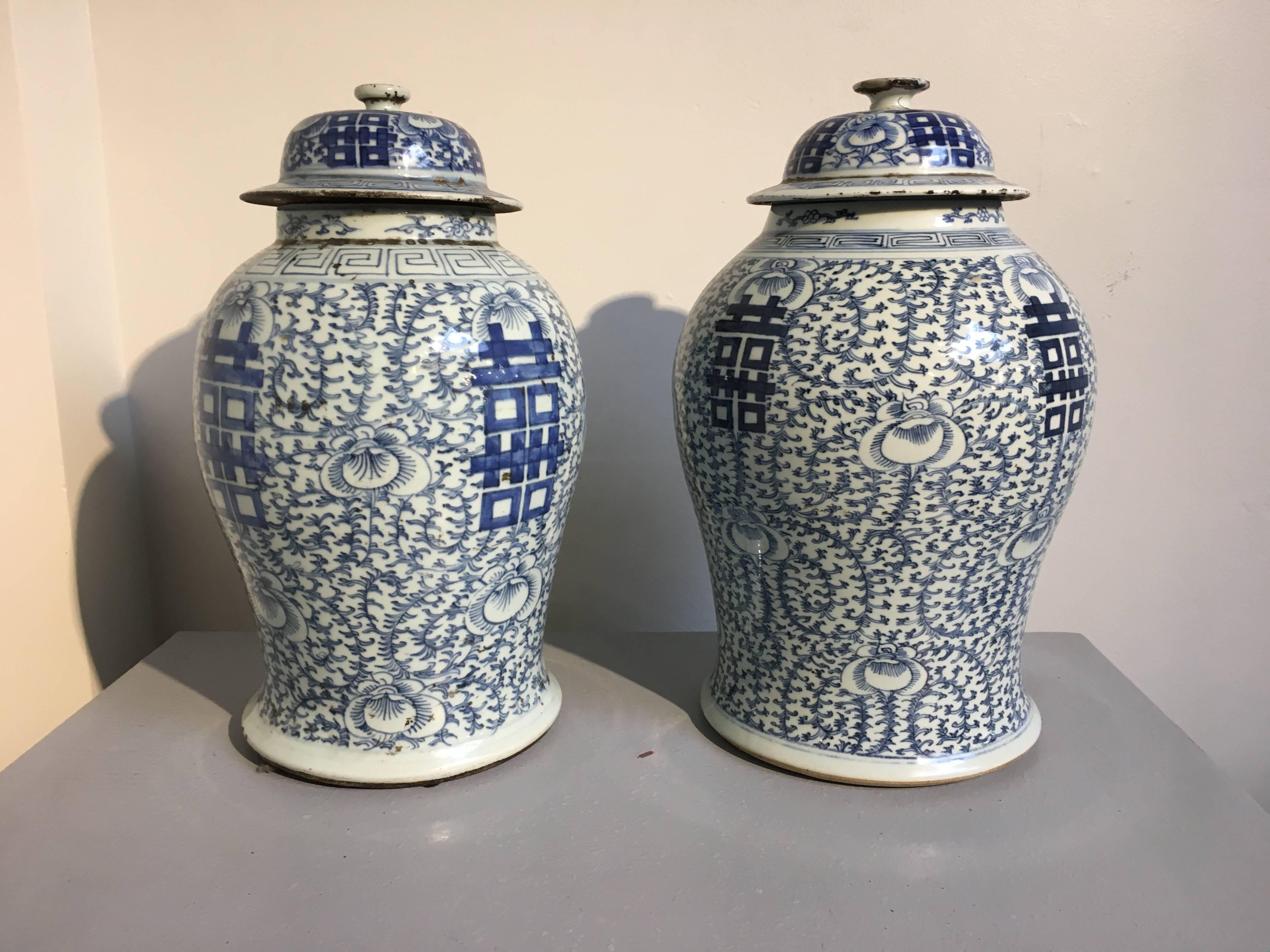 A near pair of Classic Chinese blue and white covered temple jars. The jars of elegant baluster form, painted in rich cobalt blue with large Chinese double happiness characters and intricate scrolling floral and foliate pattern against a white