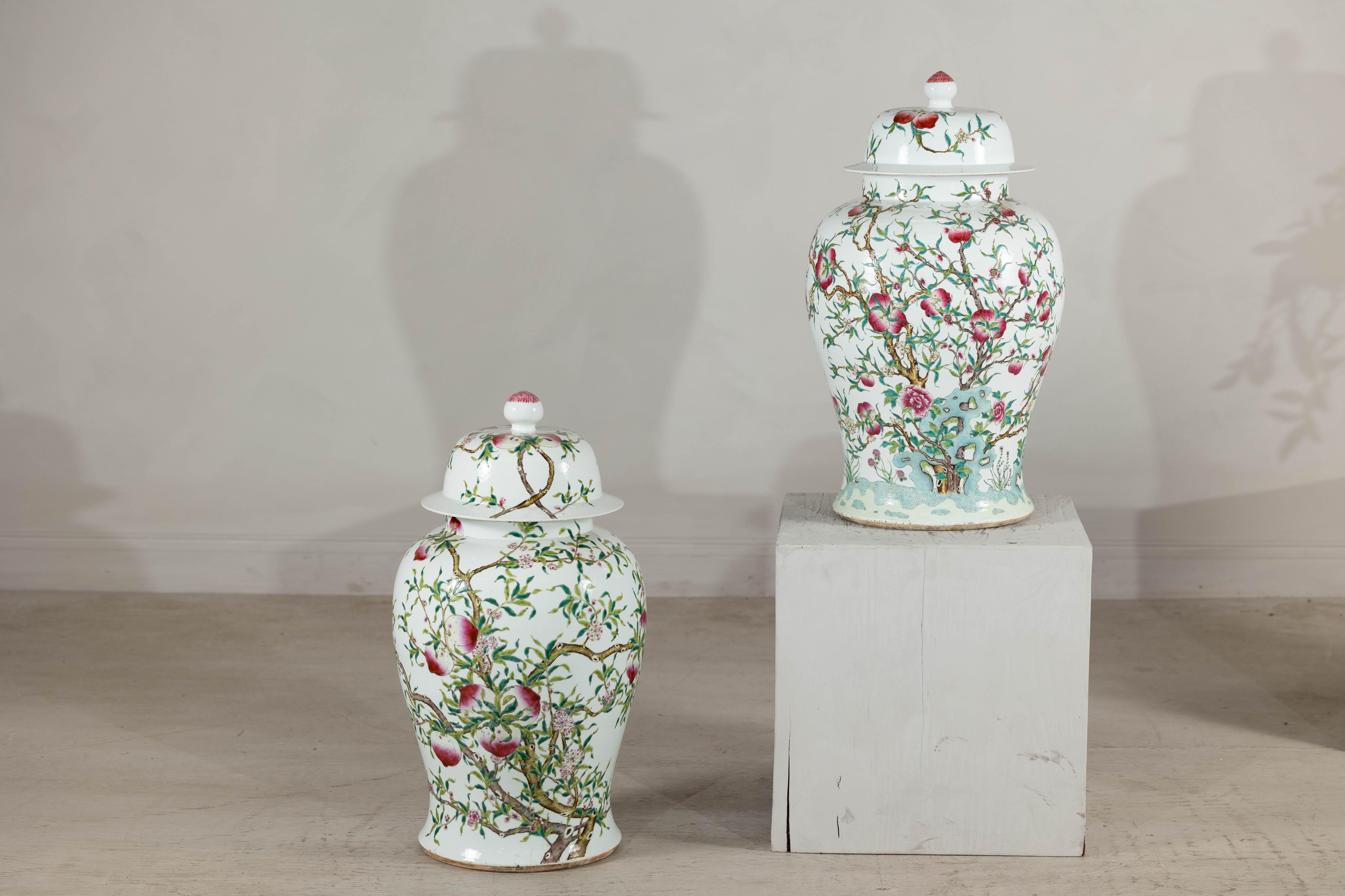 Esta pareja cercana de antiguos frascos de jengibre de porcelana china presenta una exuberante paleta de rosas de familia con motivos auspiciosos. Cada tarro está pintado a mano con ramas fructíferas de melocotón, símbolo tradicional chino de