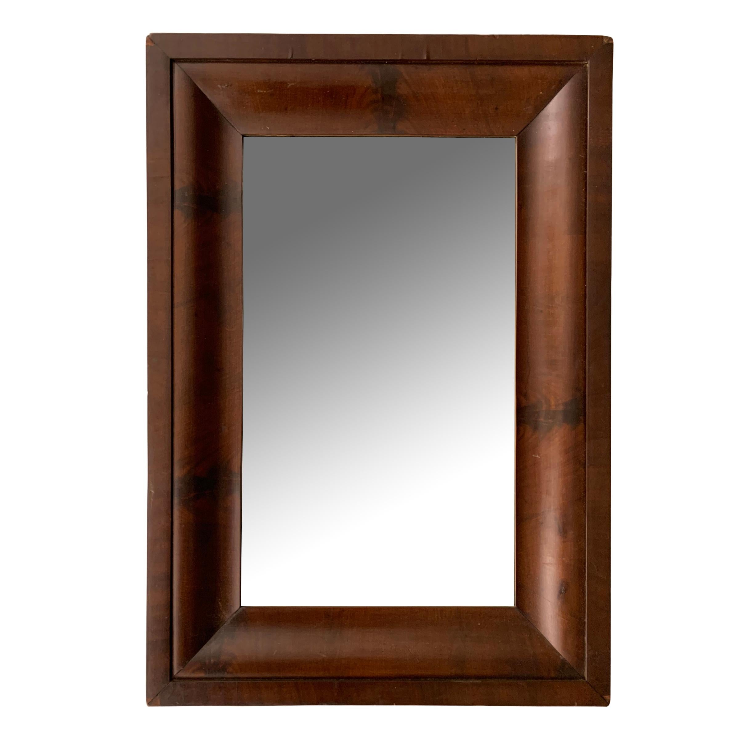 A near pair of early 19th century American Empire wide crotch mahogany veneer framed mirrors with wonderful figural grain patterns. Perfect over a pair of console or bedside tables!