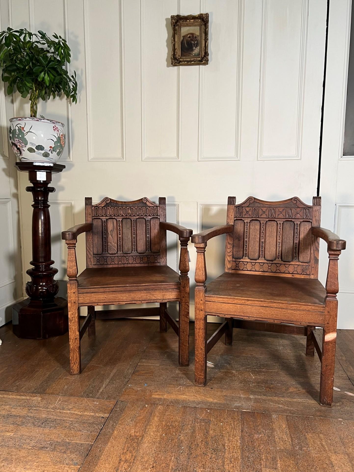 Near pair of early 20th century oak hall chairs.

Purchased from Bishton Hall, Staffordshire, UK. 

Top quality sturdy armchairs with geometric relief carving.

Measurements: 82cm H x 57cm W x 44cm D
(Measurements are approximate and are