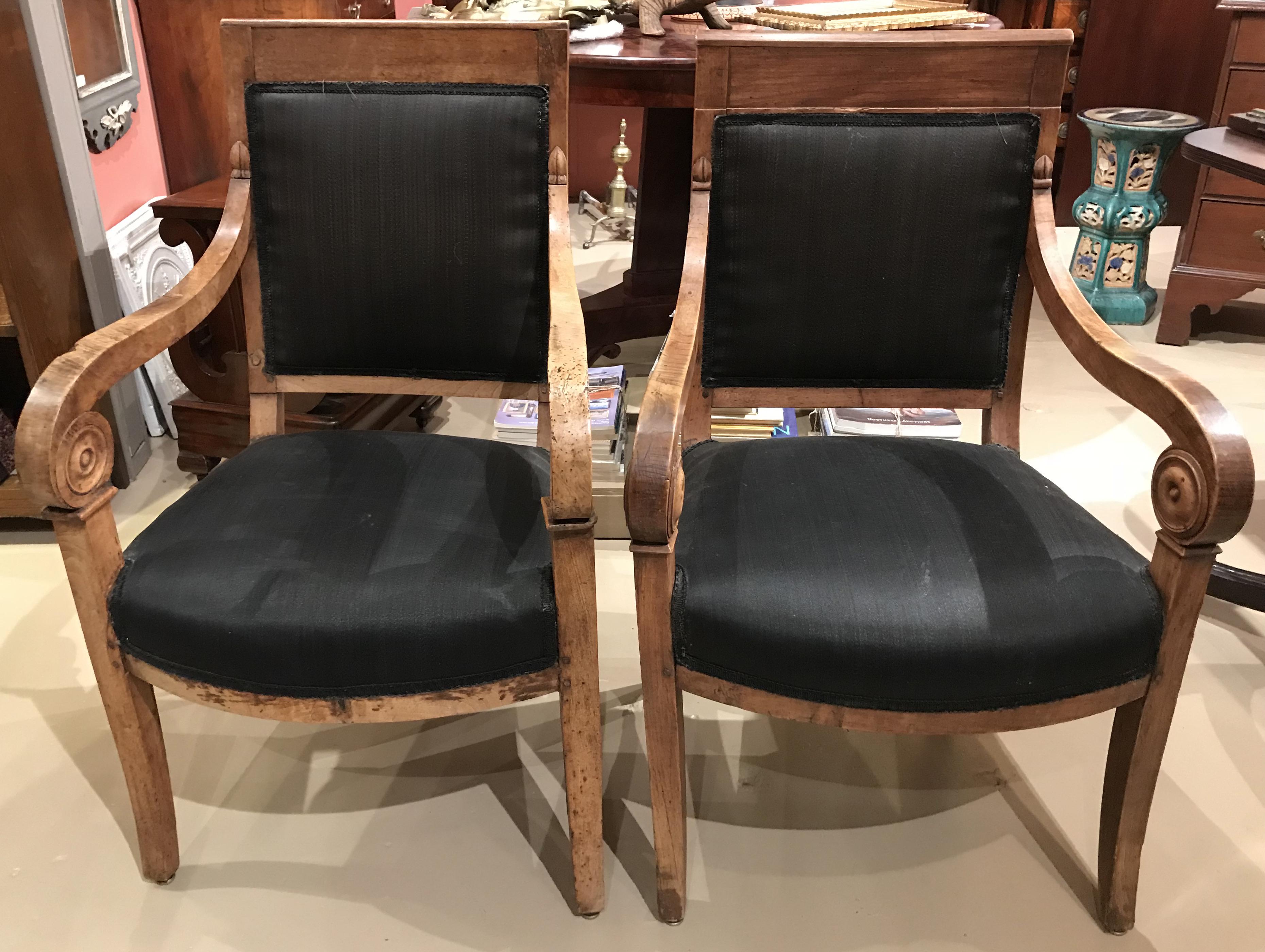 A fine near pair of fruitwood Empire armchairs with scrolled arms. Very good condition, with fresher black upholstery, some minor worm damage, other edge imperfections and light overall wear from age and use. Dimensions: Left chair is slightly