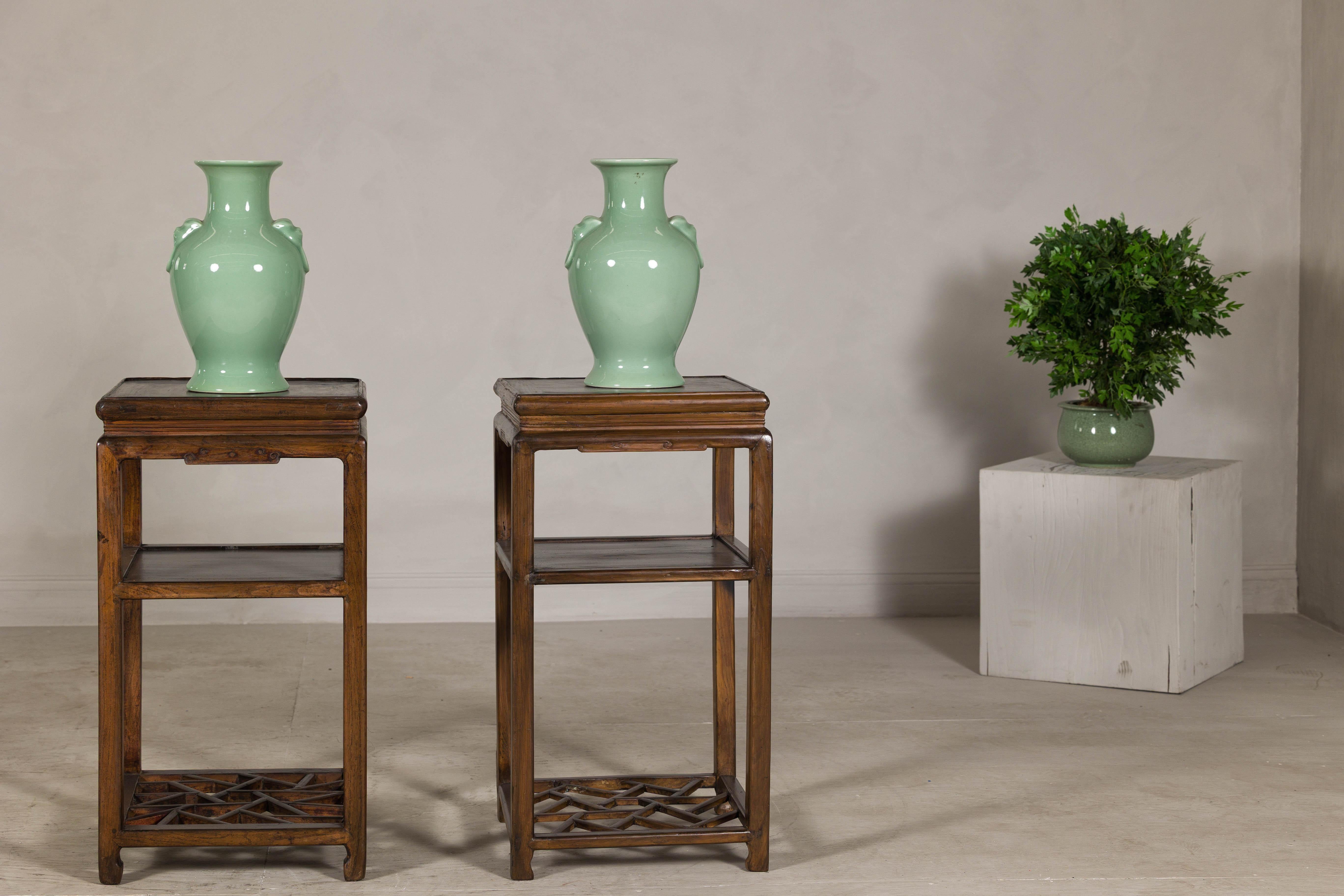 This near pair of vintage end tables brings a sense of refinement and architectural character to any interior. Crafted in hardwood with a warm, hand-rubbed finish, each table features three tiers, including a beautifully carved fretwork geometric