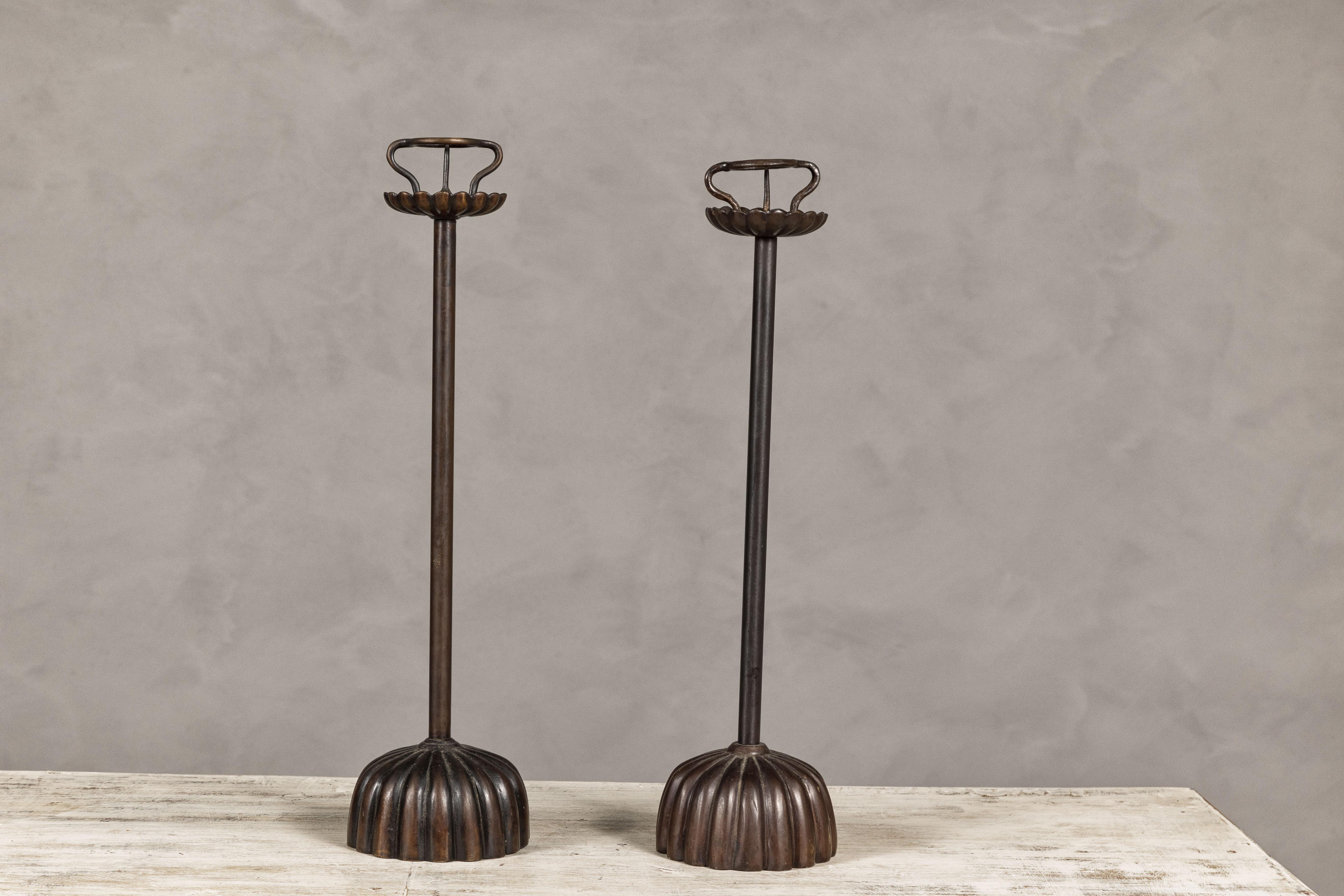 A near pair of Japanese metal candleholders from the mid 20th century with gadrooned bases. This near pair of mid-20th century Japanese metal candleholders captivates with its simplicity and attention to detail, featuring elegantly gadrooned bases