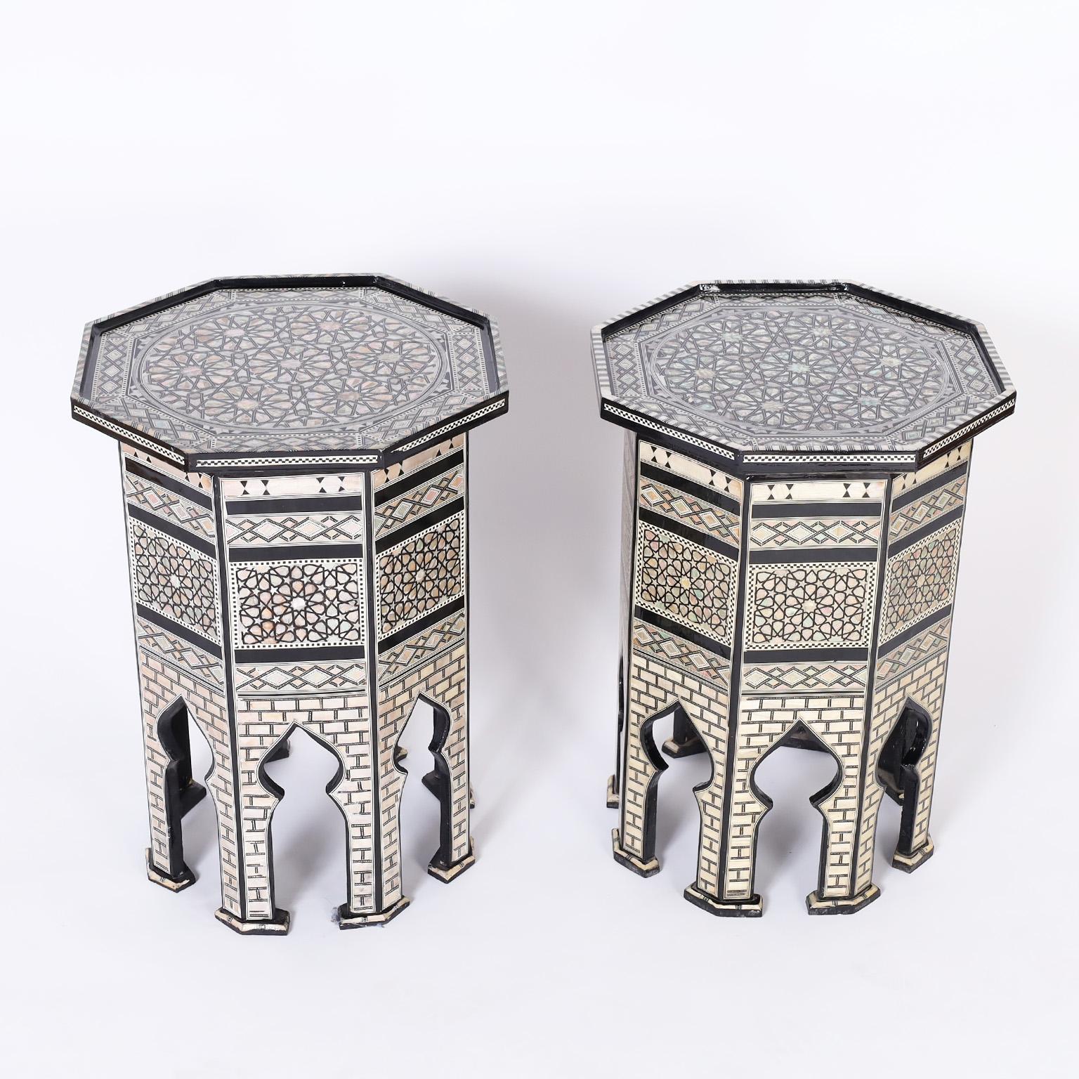 Near pair of octagon form Moroccan stands crafted in indigenous hardwood lacquered black and featuring geometric mother of pearl marquetry on the top and sides with Moorish arches between the eight legs. 

Left to right:

H: 23.5 W: 17 D:1