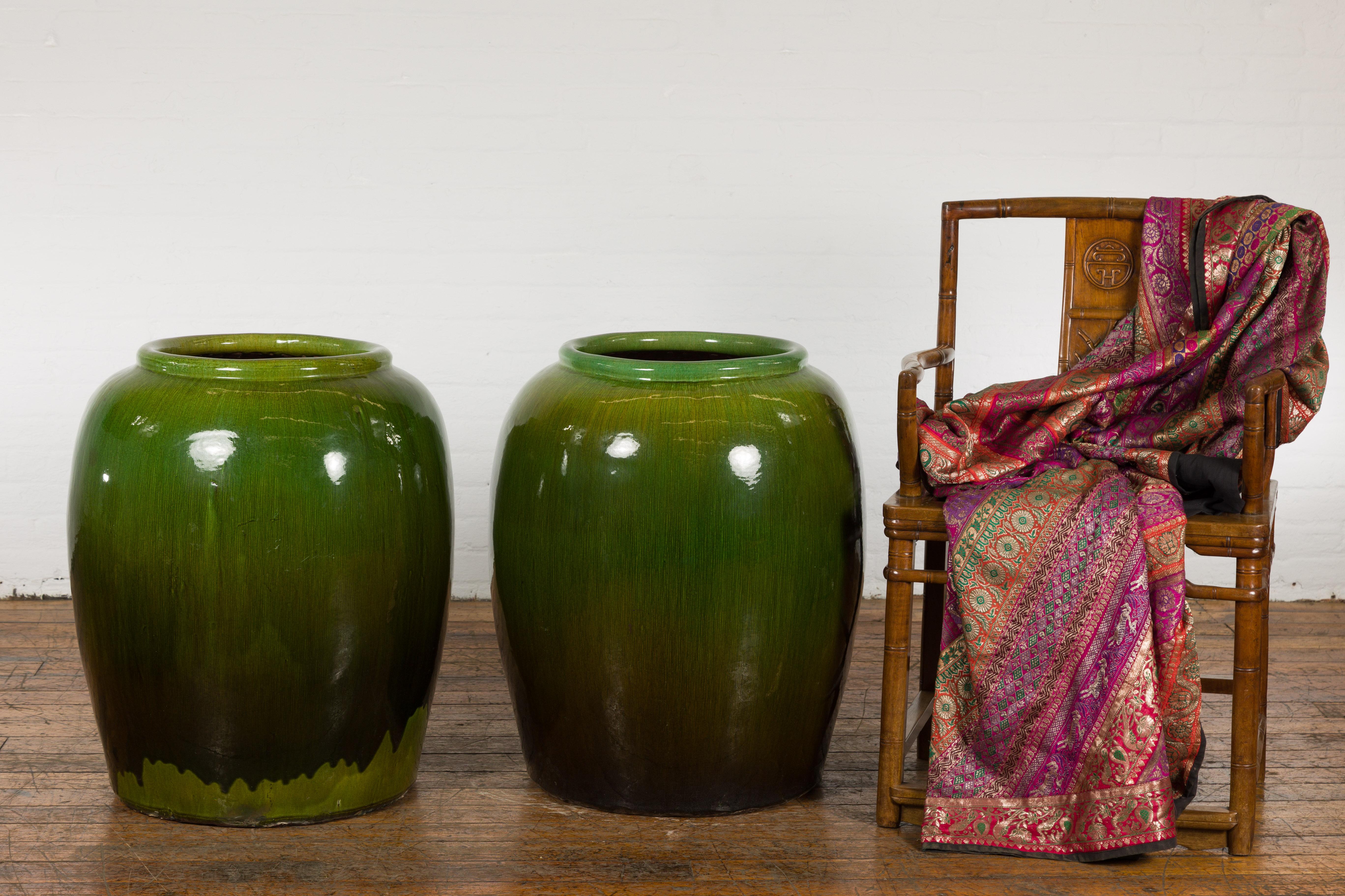 A near pair of large Chinese vintage glazed water jars from the mid to late 20th century, with apple green glaze and brown tones, perfect to be used as planters. Created in China during the third quarter of the 20th century, these two water jars