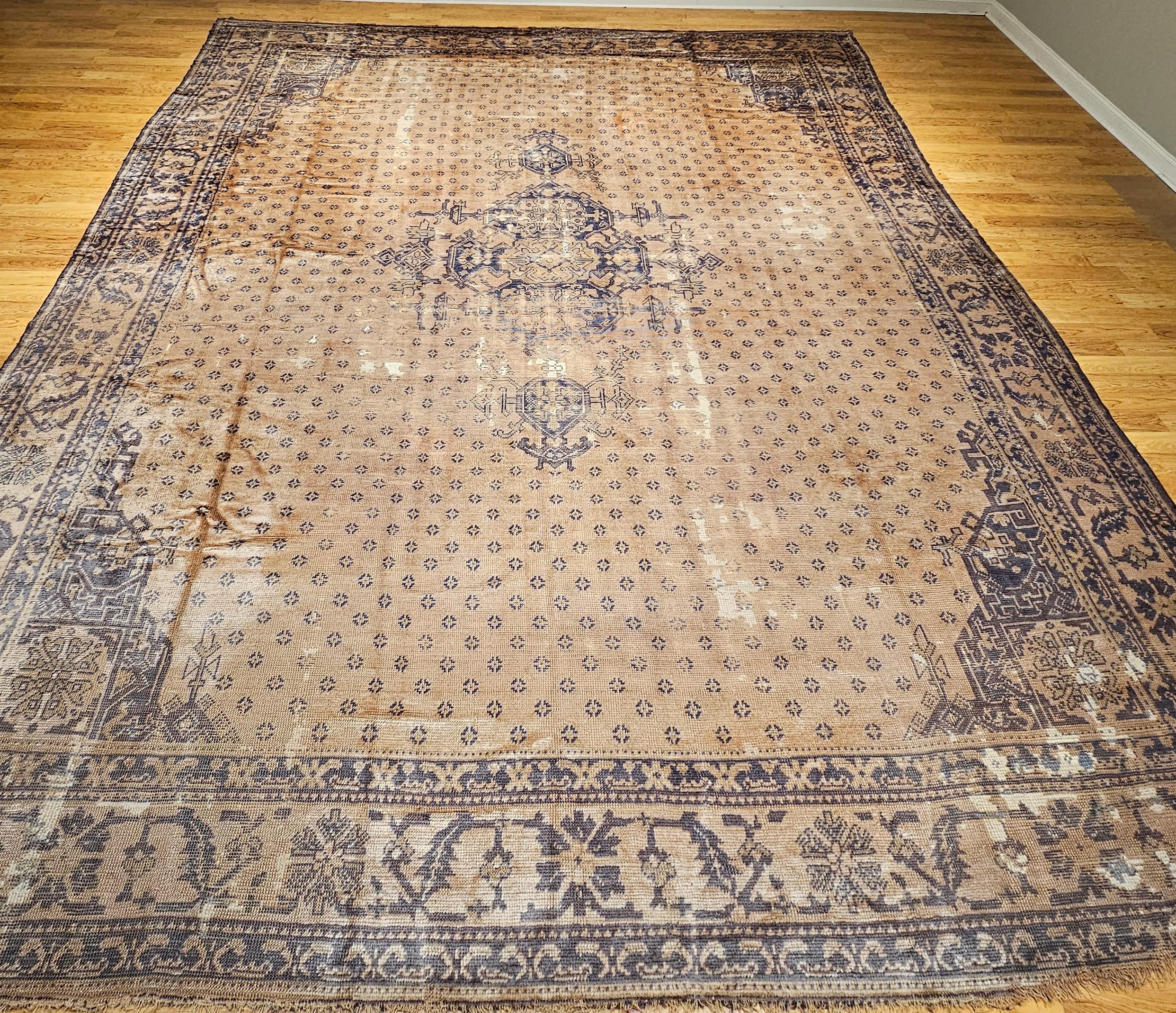 Rare and highly desirable “near square” oversized Oushak from the early 1900s.   The rug has an all-over design with a small central medallion set in a pale camelhair color with a small geometric design throughout the field.  The border is in a