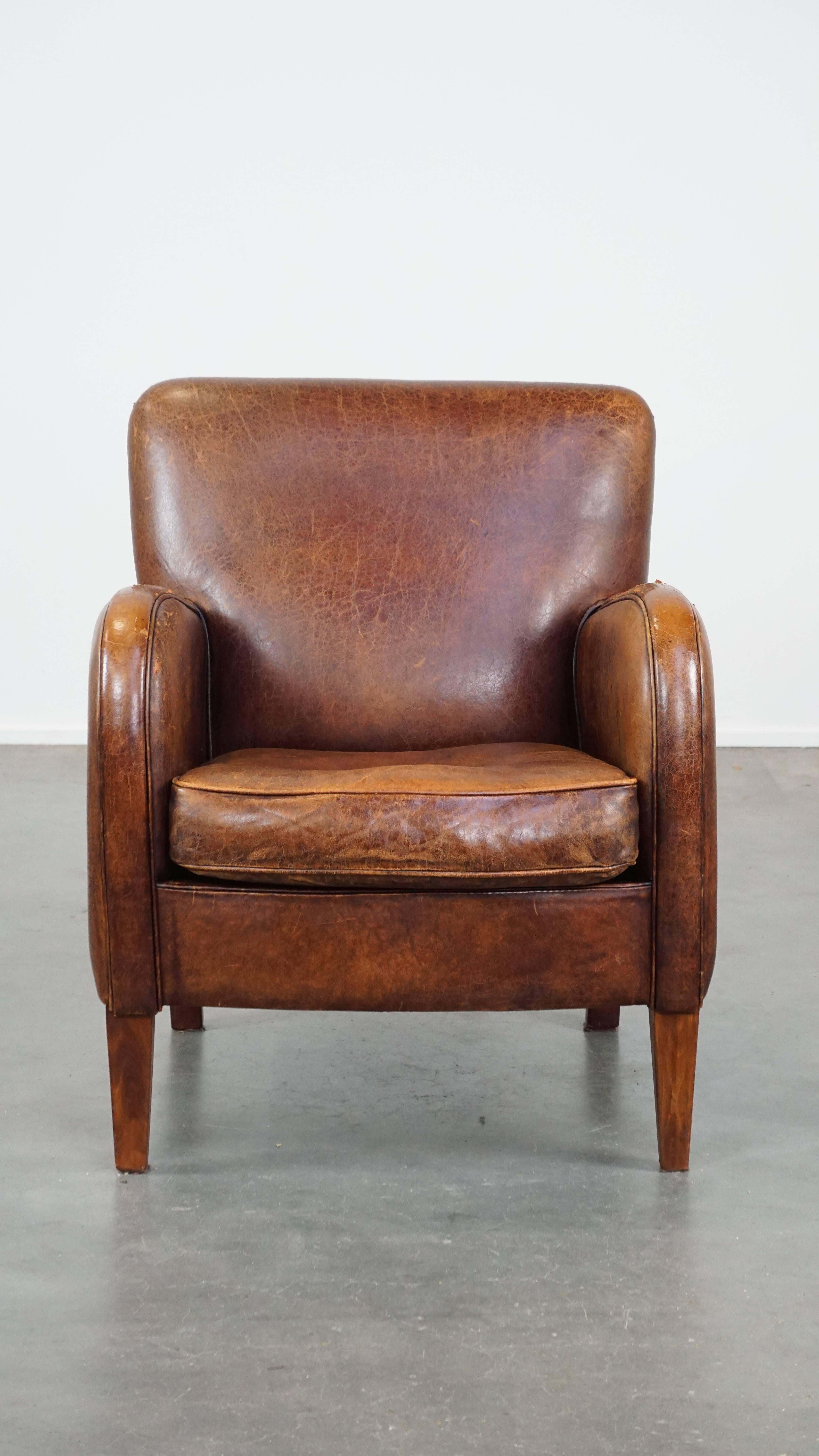 Ce fauteuil en peau de mouton aux finitions soignées est plein de caractère et a donc un aspect unique. Il est doté d'un coussin amovible et offre un excellent confort d'assise. En raison des années d'utilisation, il présente des signes d'usure,