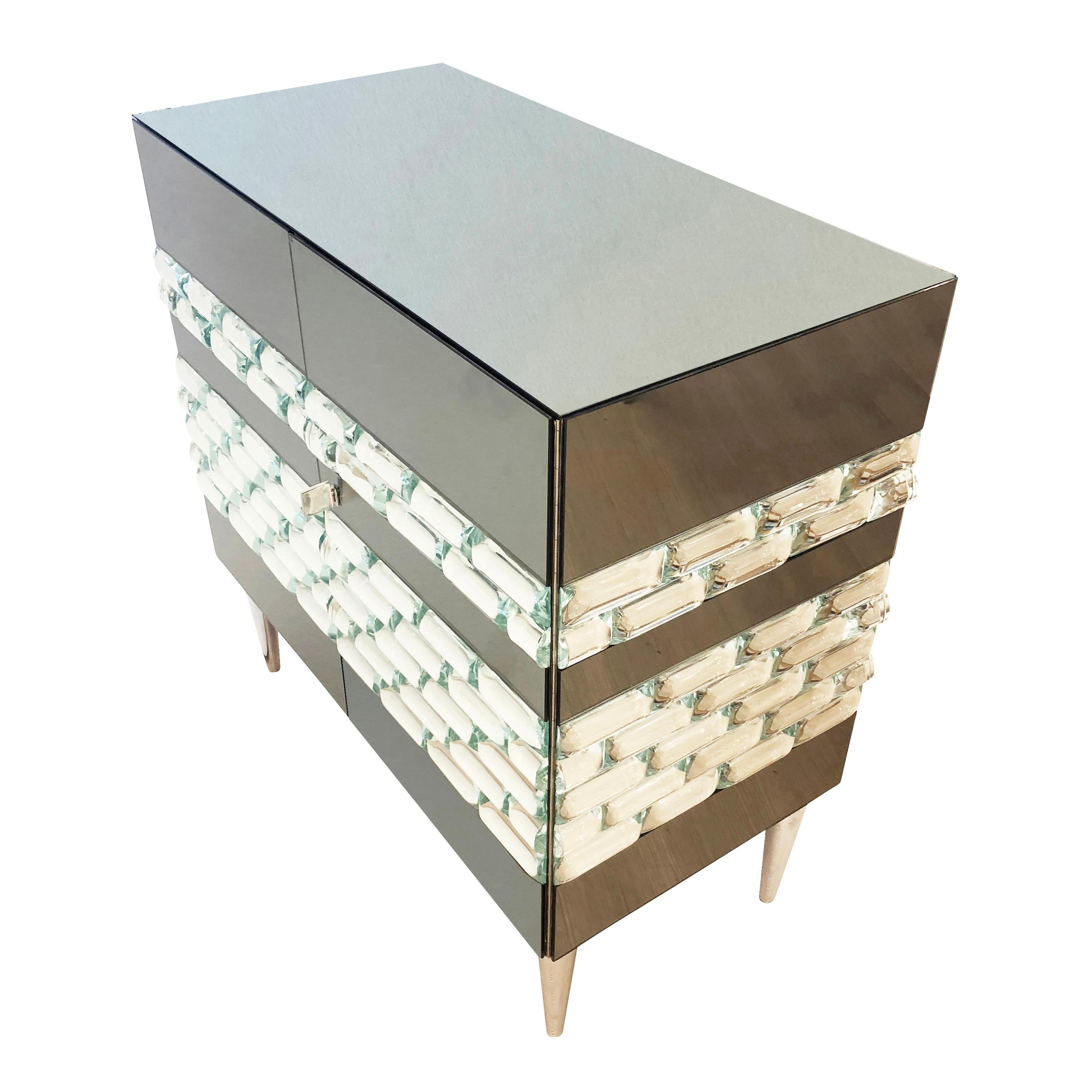 The sumptuous Nebula cabinet features gray mirrored glass paneling with hand carved starphire glass tiles.  Hardware is nickel. This is a special price for the last floor model-Original price was $9,900.00.

Width: 32”

Depth: 16”

Height:
