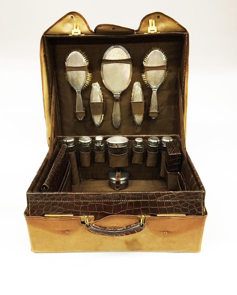 English necessaire travel case with silver and glass interior by William Neale & Son Ltd, Birmingham

Crystal glass vials that are engraved and have a silver lid or a screw cap. The inside of each lid or cap is gold plated. 1 glass object has damage