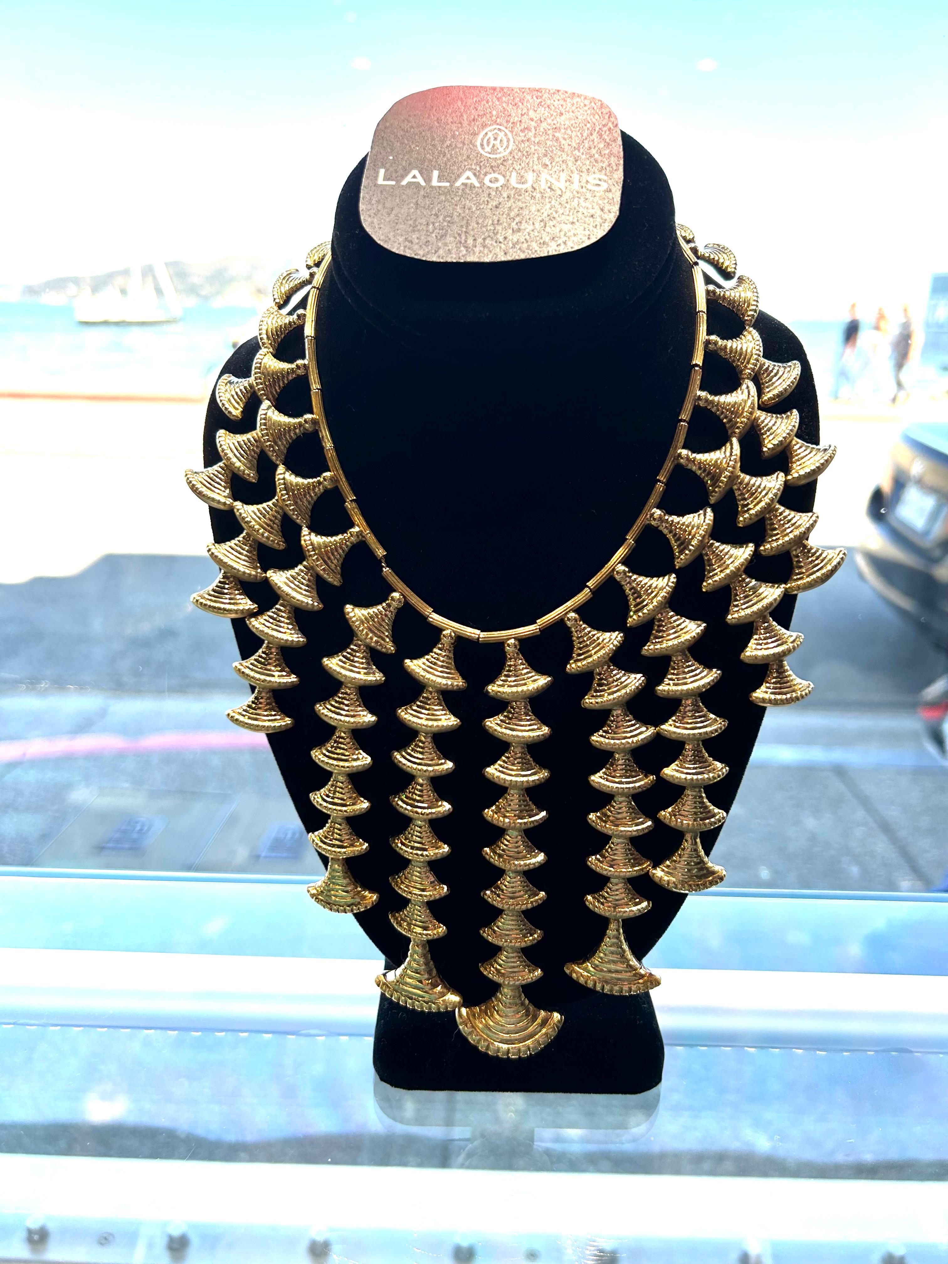 Lalaounis è una collana vintage con nappe che avvolge tutto il collo, composta da:

23 sezioni di campane gocciolanti graduate in dimensioni verso il centro.
La finitura è lucida su un lato e piatta sul lato opposto.

oro giallo 18k 

205,3 grammi 
