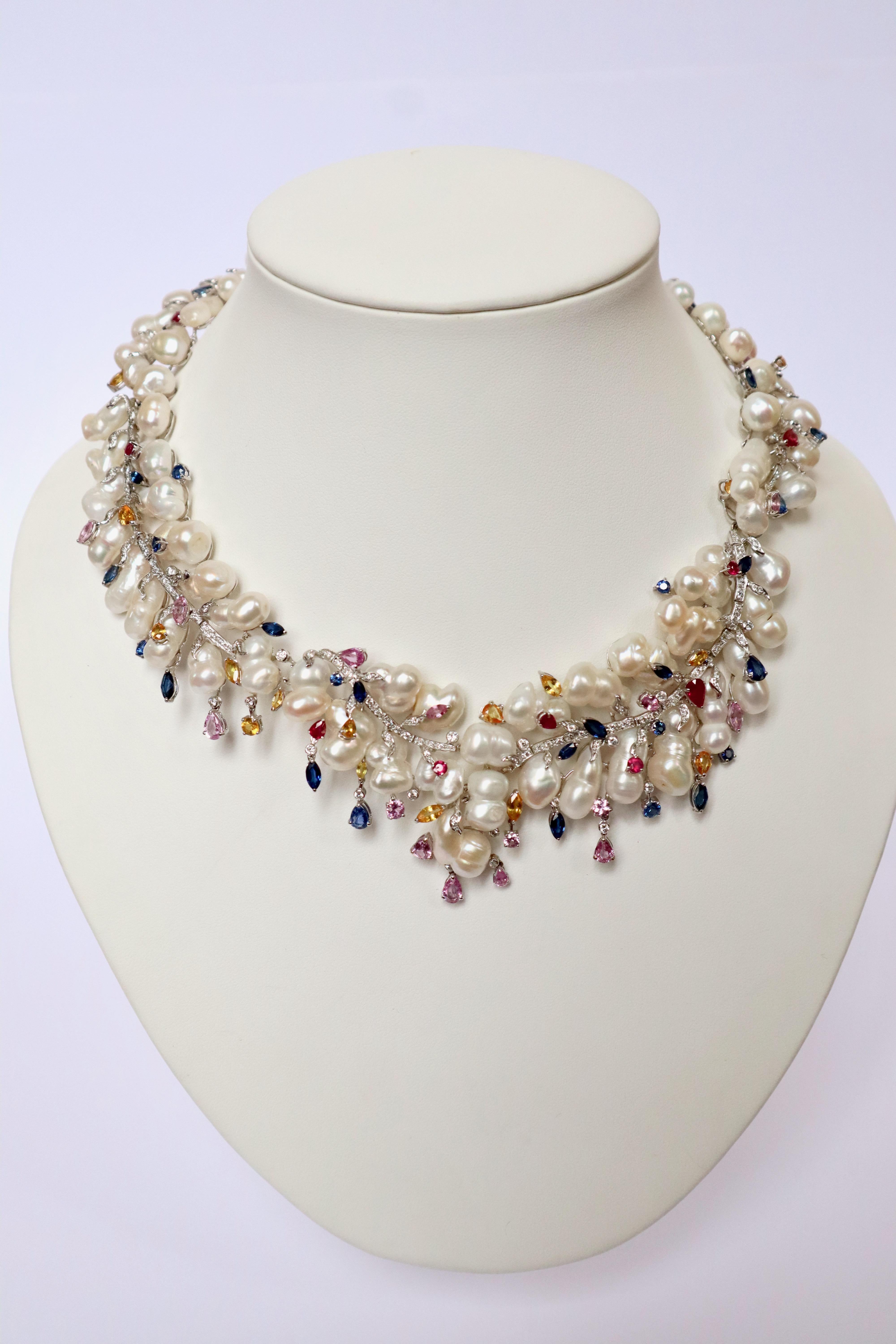 Semi-rigid articulated necklace in white gold, baroque pearls, diamonds and multicolored sapphires. It is composed of 78 baroque pearls held by white gold branch-shaped ties set with diamonds sprinkled with multicolored sapphires, claw-set. Weight