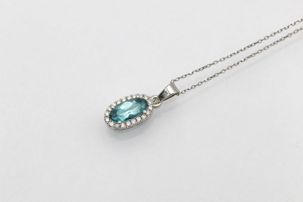 Ciondolo con tormalina Paraiba ovale del peso di circa 0,60 ct, circondata da diamanti del peso totale di circa 0,10 ct. La tormalina Paraiba si distingue per il suo unico colore 