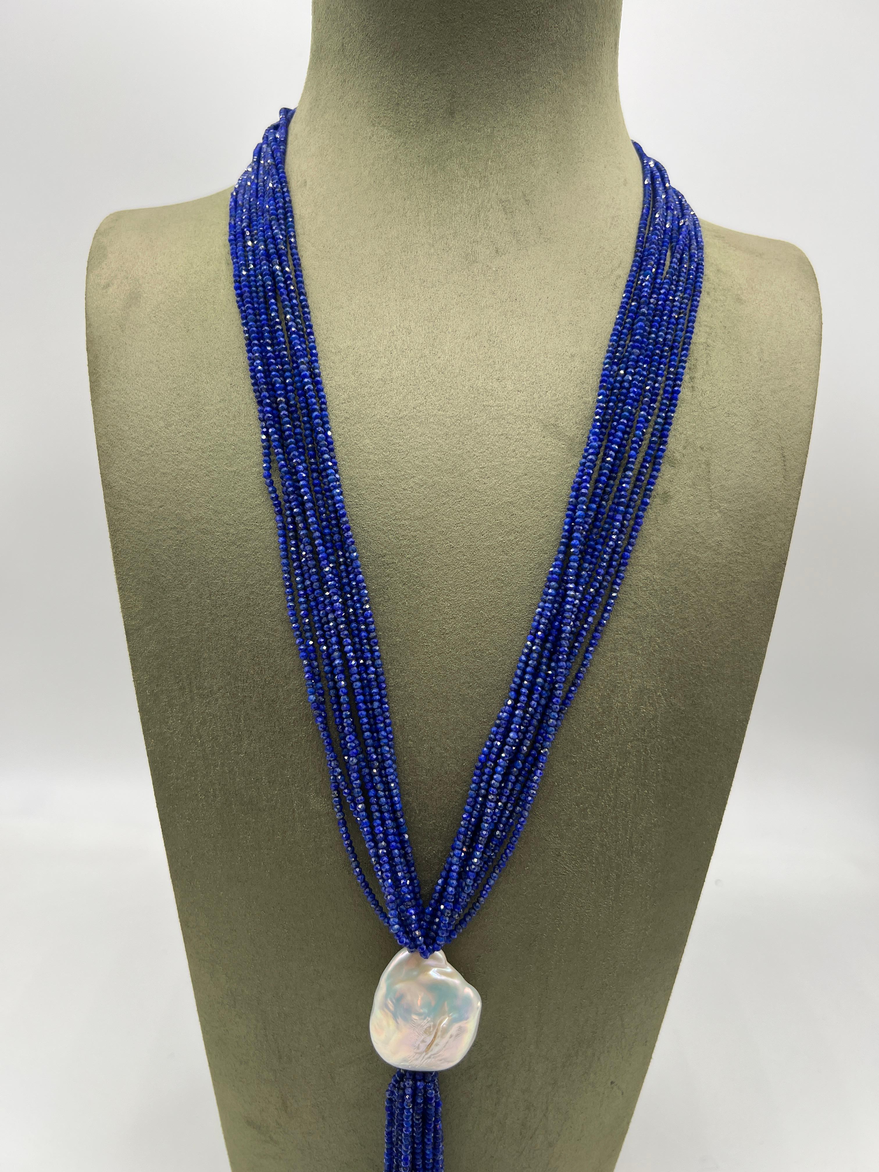 Collana lunga lapislazzuli Perle barocche Bakelite Questa elegante collana lunga è realizzata con perle di lapislazzuli. Presenta una moltitudine di frange di perle che si uniscono su un'unica perla bianca barocca. La frangia cadente aggiunge un