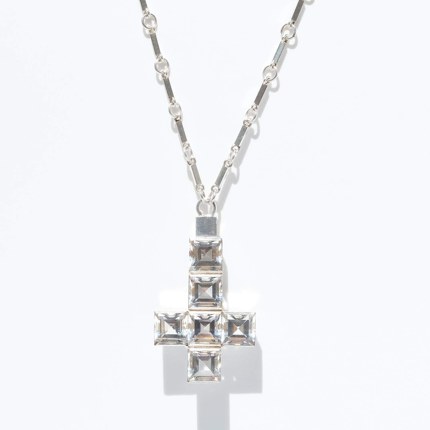 This sterling silver necklace shows upon typical Wiwen Nilsson characteristics; the geometric lines, the clean-cuts, the modern design and brushed silver, the square faceted cut rock crystals and the ring and bar chain.  

The only way to describe