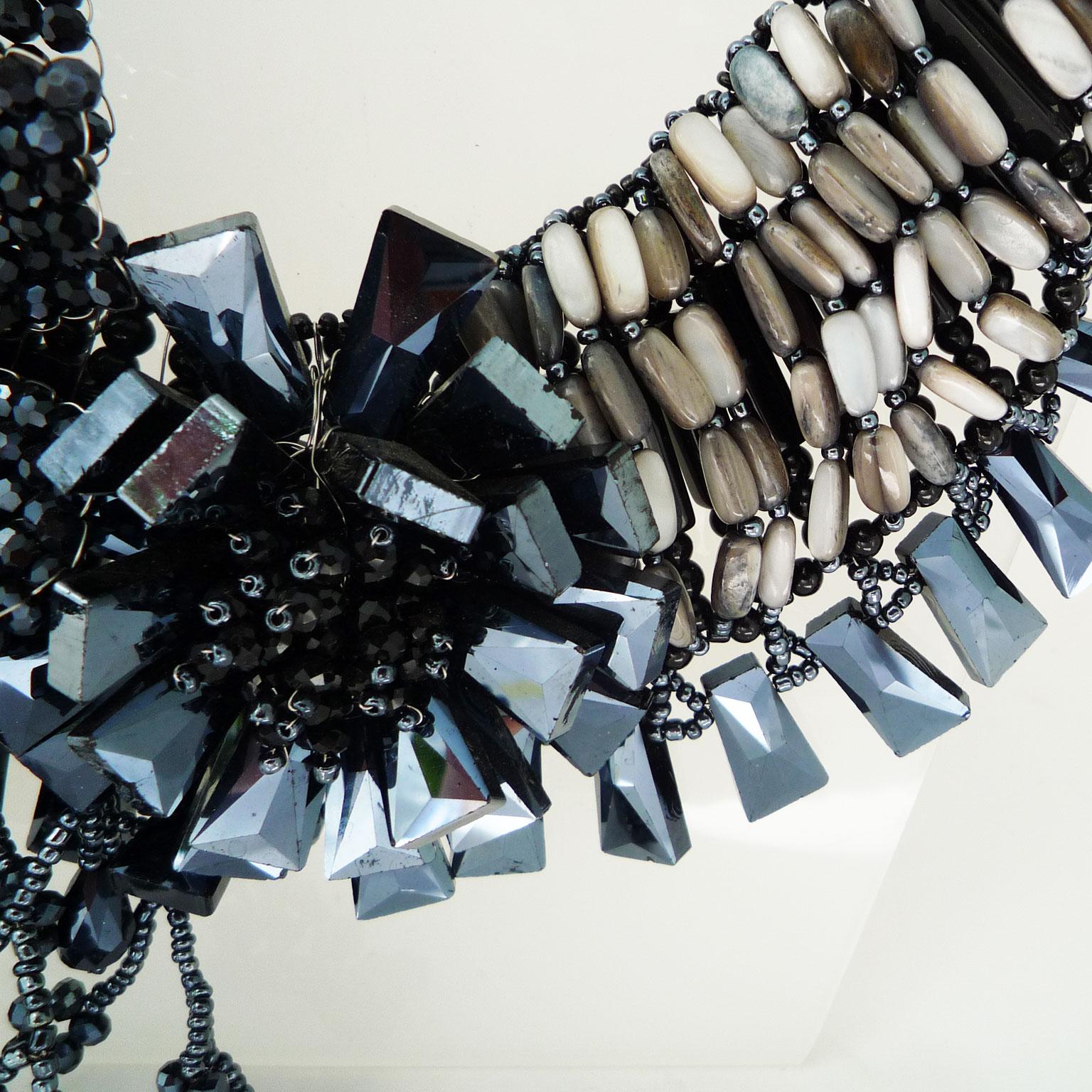 Halskette aus schwarzem Kalkstein und schwarzen Swarovski-Perlen
Handgefertigte Kette aus schwarzem Kalkstein. An die Kette wurden kunstvoll florale Elemente geknüpft. 
Die Farbe von reinem, unverfälschtem Kalkstein ist weiß, während die Anwesenheit