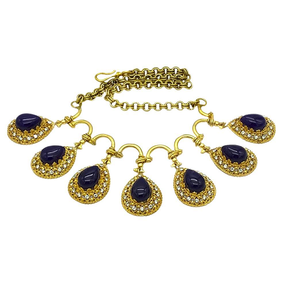 Questa è una collana con ametista e placcatura in oro 14K. La collana a catena è collegata a sette grandi gocce di ametista viola intenso (8 x 18 mm), ciascuna circondata da strass trasparenti. Le maglie metalliche delle gocce evocano l'architettura
