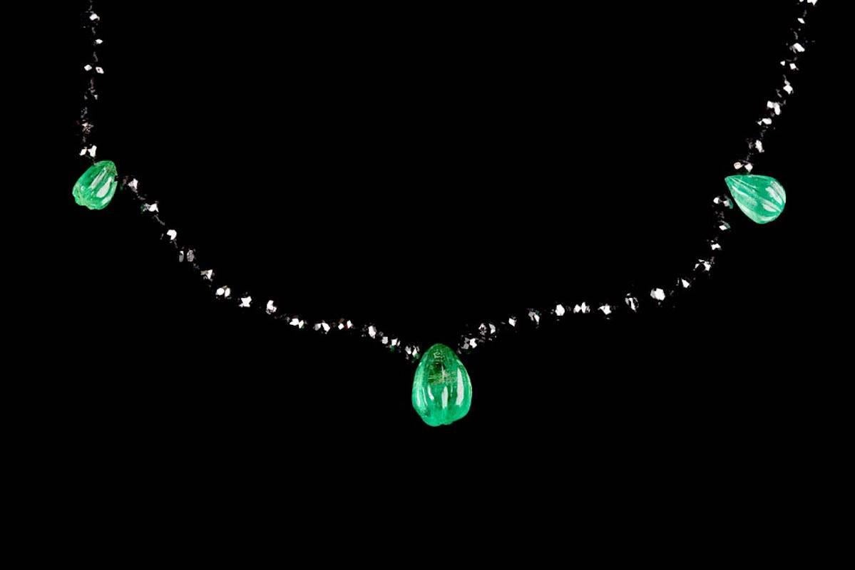 Contemporary design 21.5 carat graduated black diamond necklace with 5 gadrooned pear shape emeralds and silver clasp.