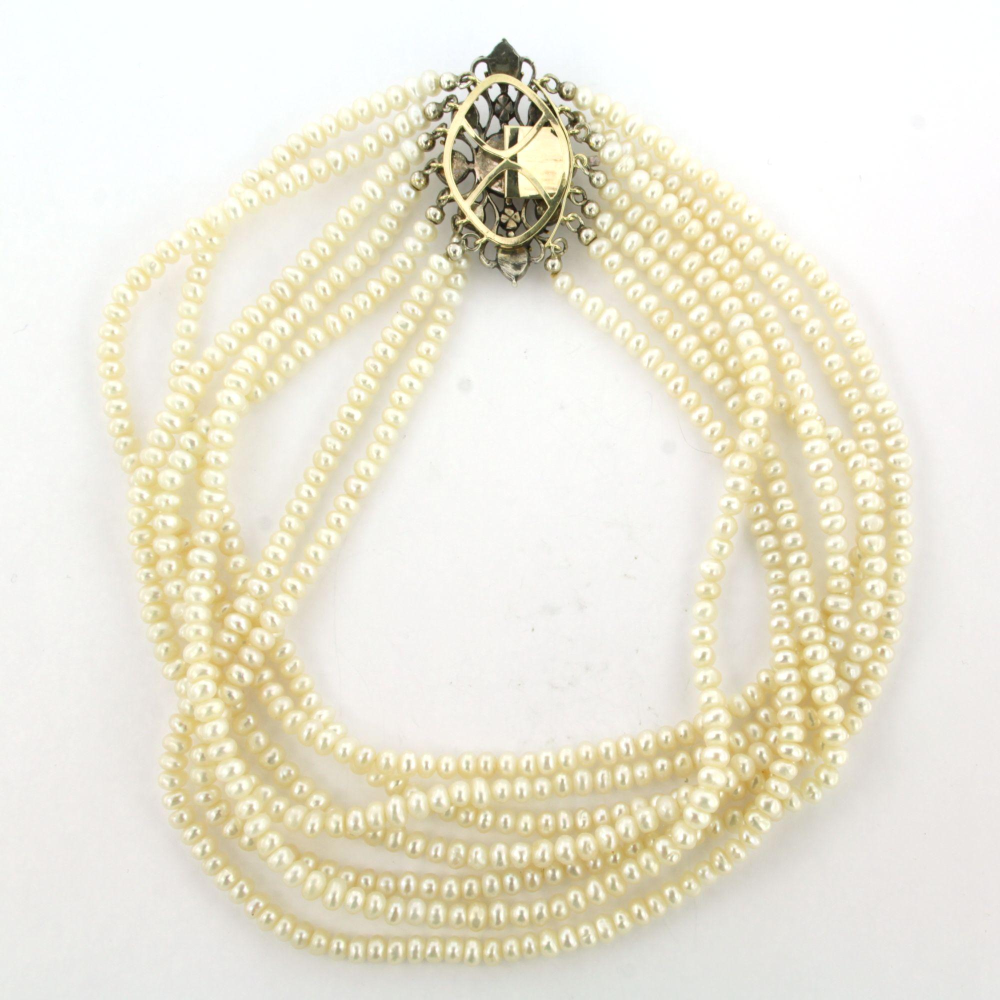14k yellow gold with a silver clasp set with rose diamonds up to 0.60 ct on a 7-strand pearl necklace – 35 cm long

Detailed description

The necklace is 35 cm long and 3.2 cm wide

The clasp measures 3.8 cm and 2.4 cm wide

Total weight: 68.4