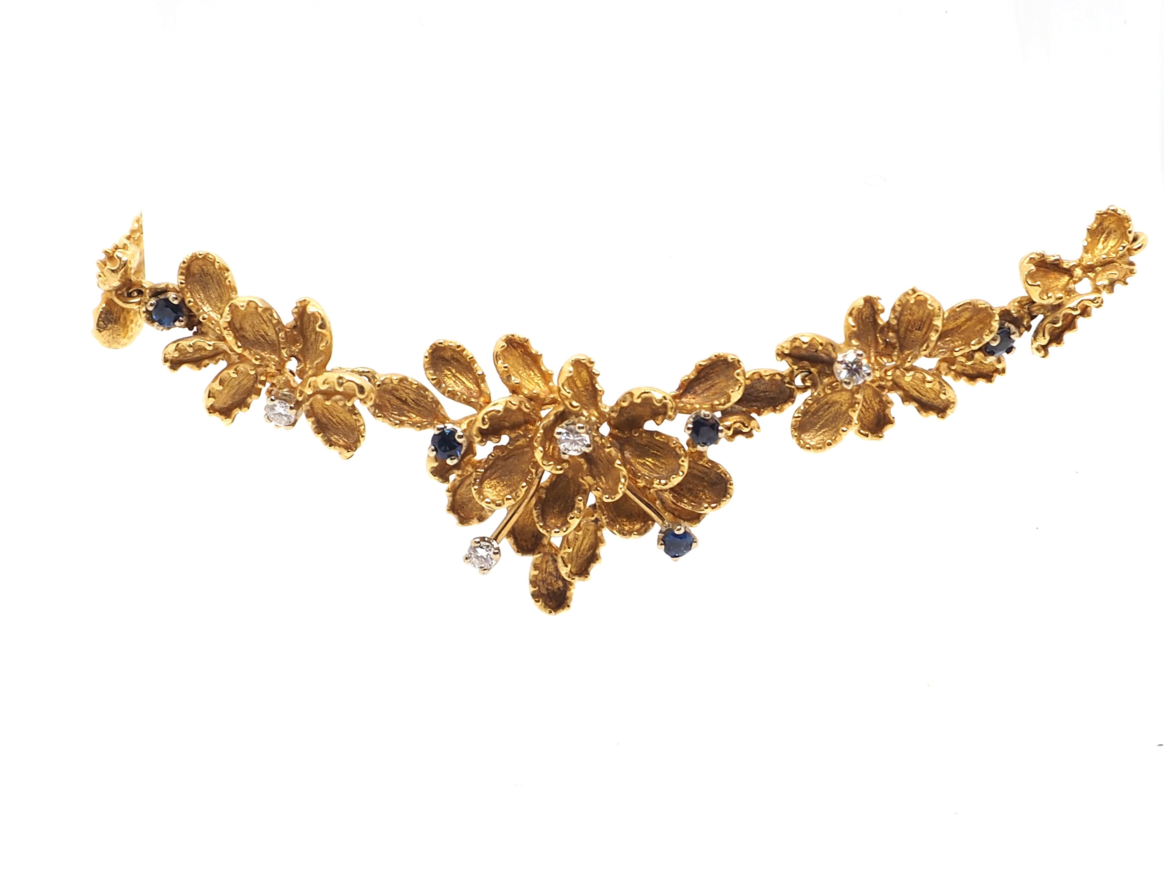 Diese exquisite florale Halskette mit Rubinen und Diamanten ist aus 18 Karat Gelbgold gefertigt und strahlt einen warmen und luxuriösen Glanz aus. Das Herzstück dieses atemberaubenden Schmuckstücks ist eine Reihe fein gearbeiteter Blumen, deren