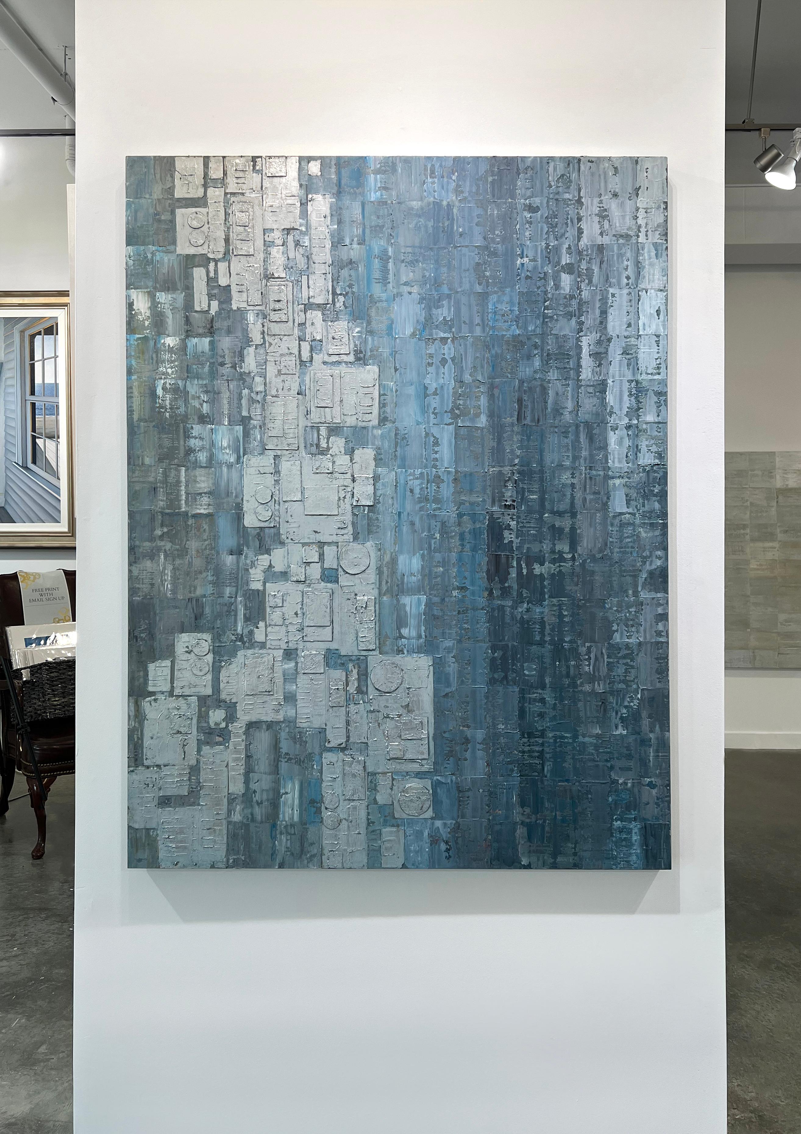 This abstract, contemporary painting by Ned Martin features a blue and silver palette. Varying shades of blue rectangular shapes are patterned together in a loose grid formation, with silver textured rectangles and and circles overlapping as they