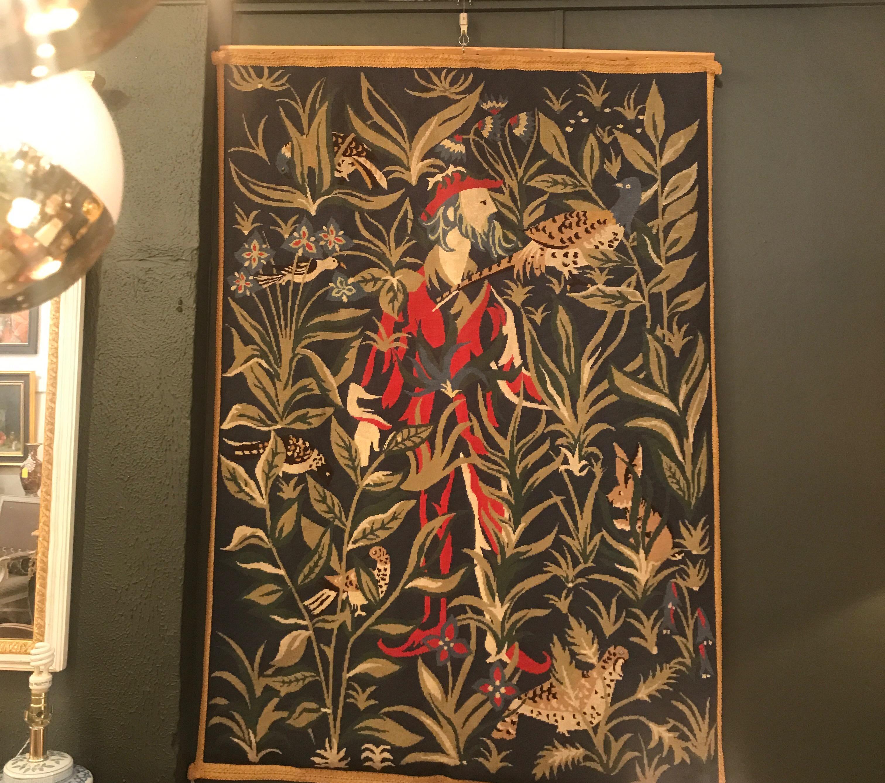 A hand embroidered wool tapestry with lining. The tapestry depicting a medieval figure surrounded by foliage with birds and small woodland creatures. The silk lining neatly stitched entirely by hand. All wool yarn.