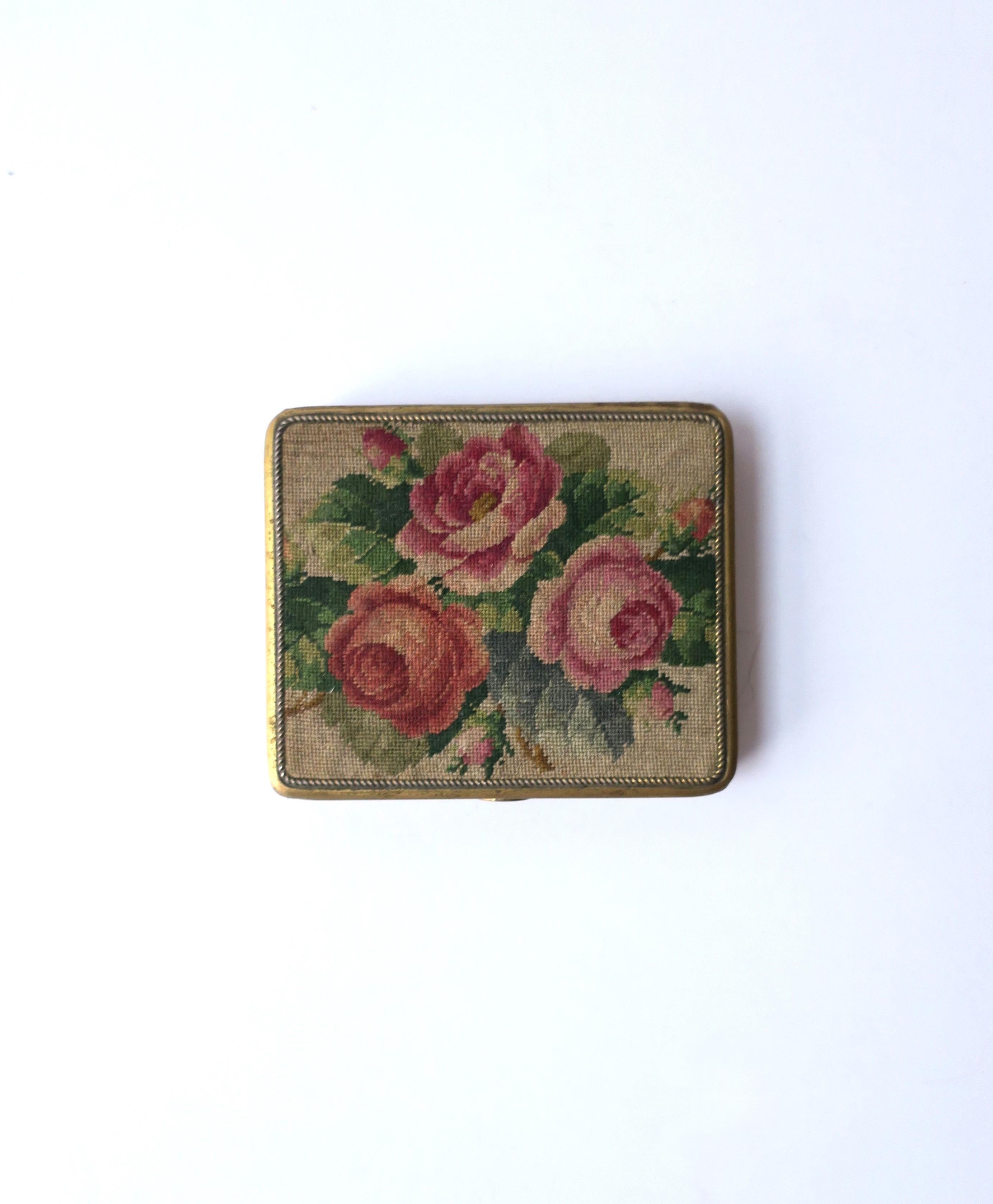 A beautiful petit needlepoint and enamel brass box with floral rose design, circa early-20th century. Lid has a beautiful petit needlepoint design of three roses, leaves and rose buds, on a neutral enamel over brass box. Marked inside box, 'Genuine