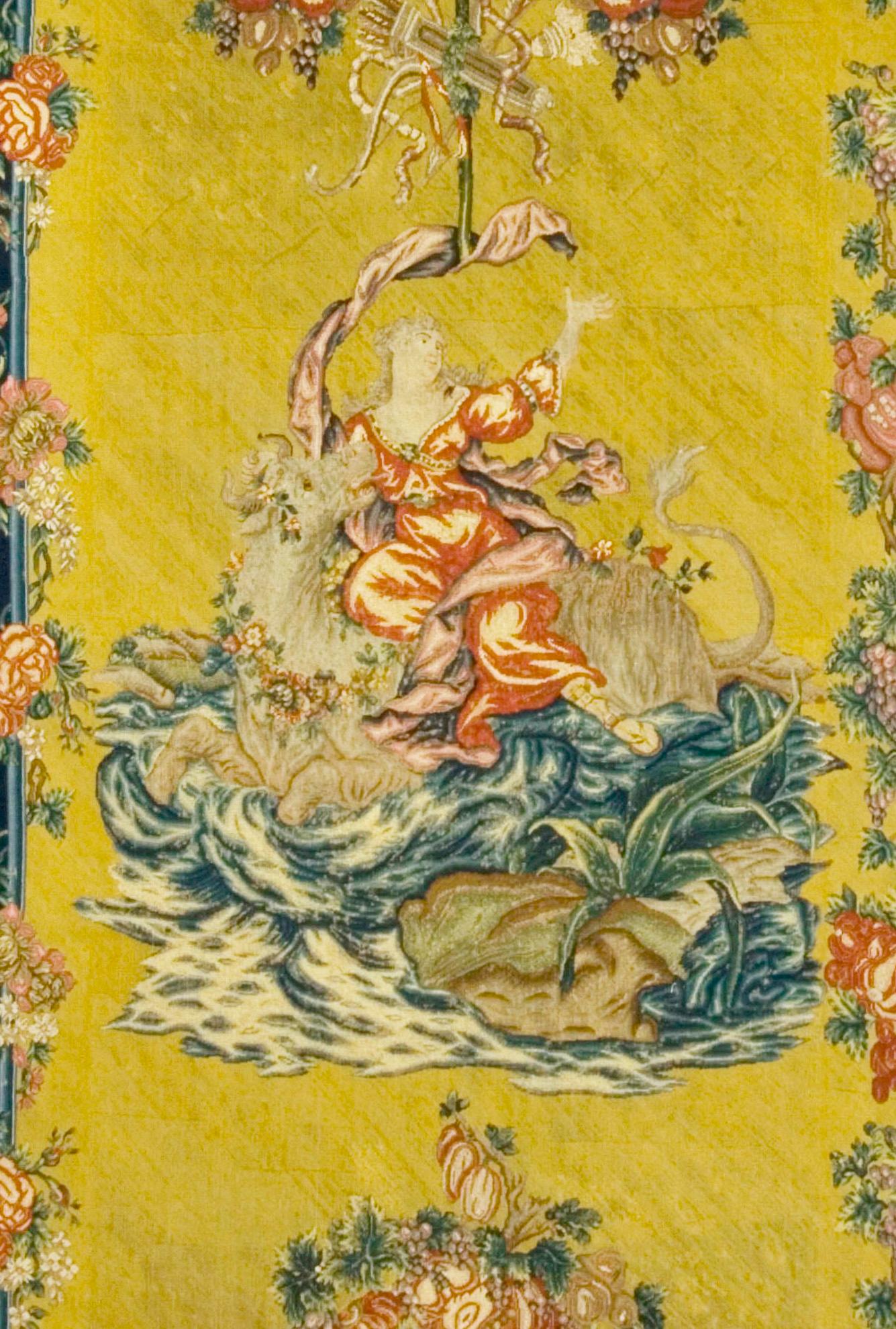 Needlepoint panel of a mythological scene in the manner of Boucher. One of a pair of arched panels possible Entre Fenetres, the orange yellow grounds display each an arch of fruits and flowers and a swag of similar character. There is a suspended