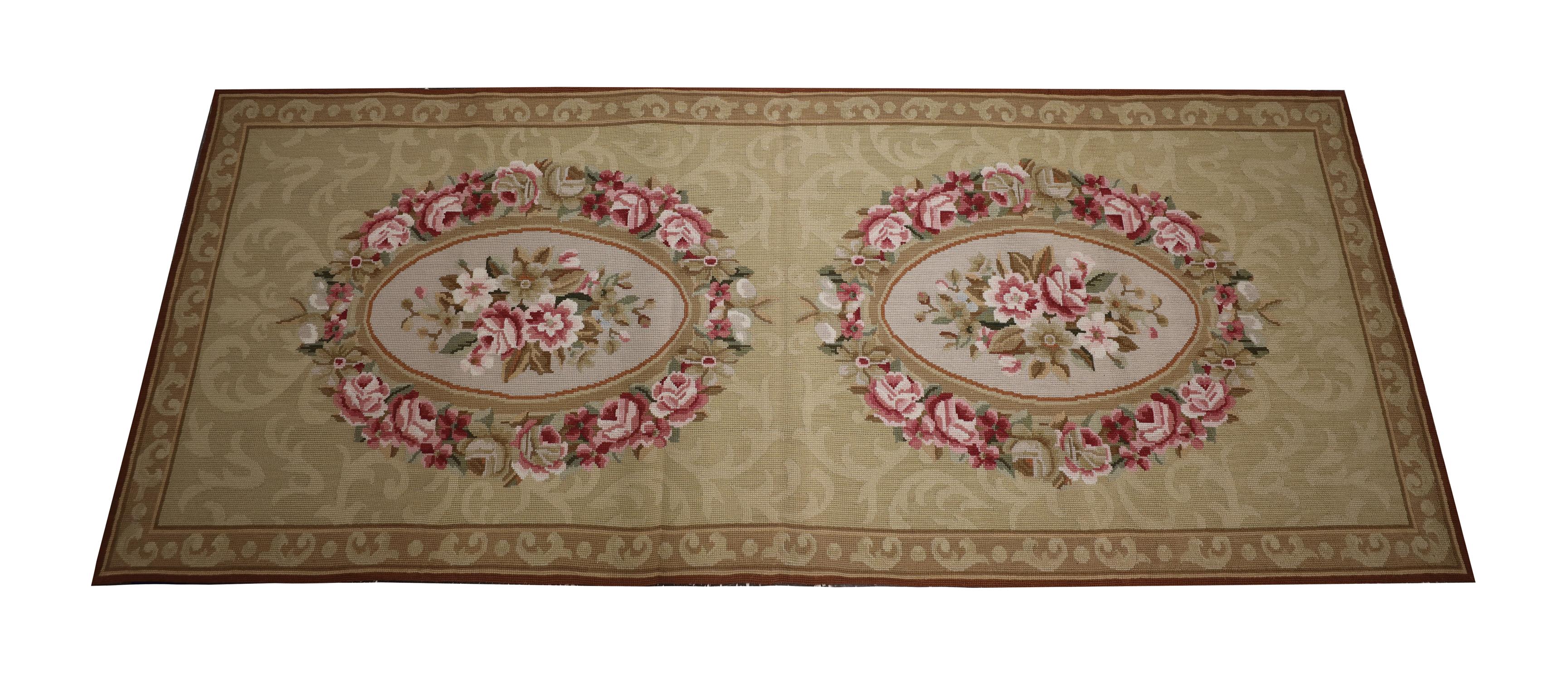 This elegant needlepoint rug was woven by hand in the early 21st century, using traditional techniques and materials. The beautiful design features two oval, floral medallions woven in pink, ivory and green accents on a cream repeat pattern