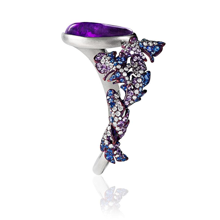The Pero Bangle by Neha Dani is set with a stunning specially carved Amethyst of 24.74 Carat on Titanium. The delicate, yet bold jewel is finely set with 1.32 Carat Round Brilliant Cut Diamonds, 2 Carat Blue Sapphires and 1.44 Carat Purple