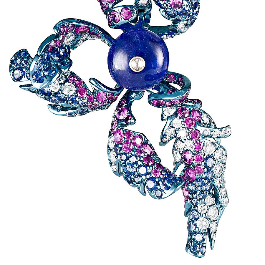 Monal Earrings by Neha Dani glitter with 3.90 Carat Blue Sapphire and 4.12 Carat deep Pink
Sapphires encrusted on swirling feathers,of Titanium set with 2.45 Carat Round Brilliant Cut Diamonds and 0.78 Carat Rose Cut Diamonds. The centre stones are