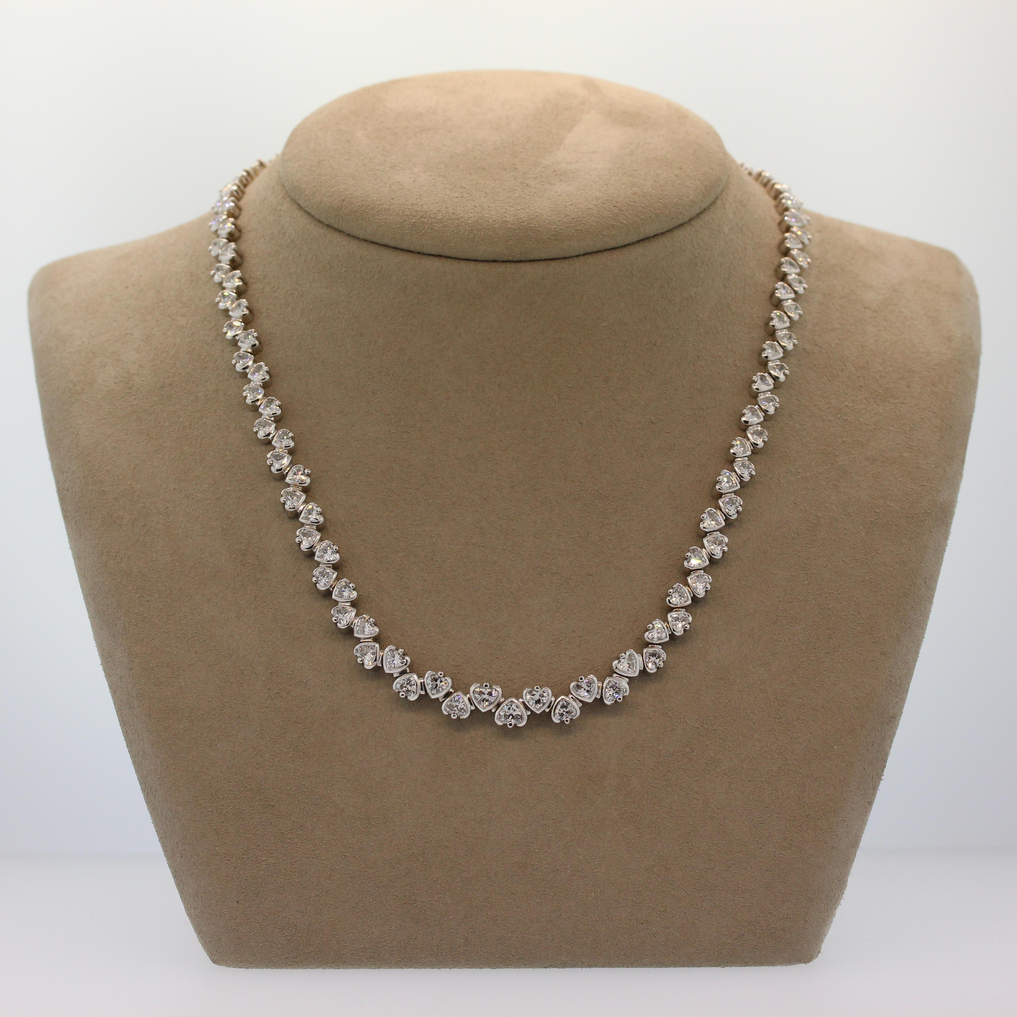 A romantic necklace by designer Neil Joseph featuring 12.75 carats of VS quality heart shape diamonds. The colorless diamonds are bezel set in 18K white gold. The linked hearts alternate with right side up and upside down giving this necklace a fun