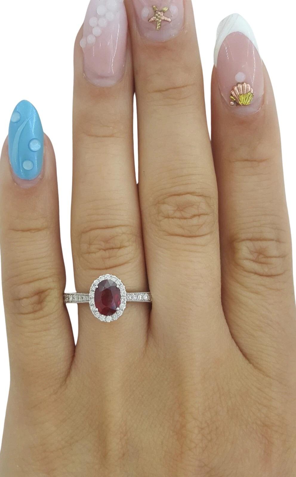 Este impresionante anillo de compromiso de Neil Lane presenta un rubí rojo natural de rico color, talla brillante ovalada, con un peso aproximado de 1,00 quilate y unas medidas de 7,22 x 5,34 x 3,2 mm. La vibrante piedra central está enmarcada por