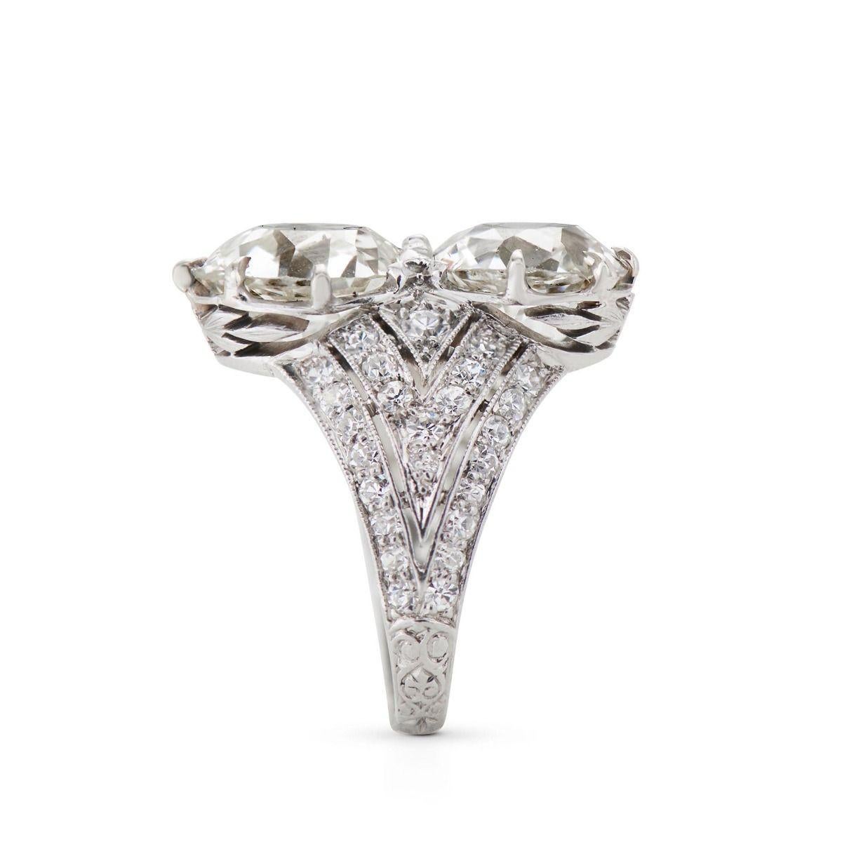 A beautiful work of art from the 1920's, this sentimental “toi et moi” design presents two old European-cut diamonds weighing 2.59 cts. and 2.70 cts. Vertically set, they are flanked by a tapering linear geometric design of 50 old European and