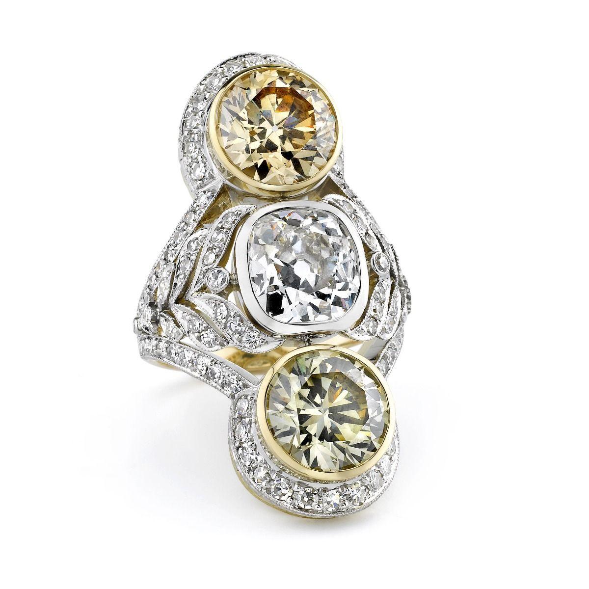 This trio of bezel-set diamonds are distinguished within this elongated Edwardian inspired ring. Designed as platinum millegraining paired with 18k yellow gold naturalistic motifs, embellished throughout by 95 round-cut diamonds weighing 0.72 ct.
