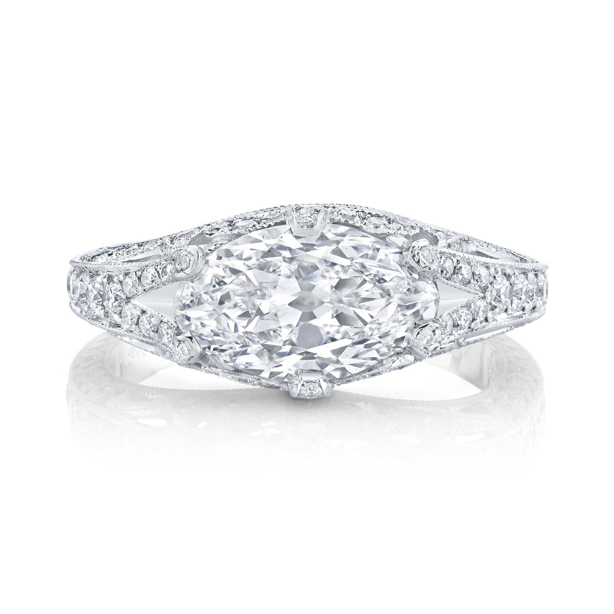 An unusual vintage “moval” cut diamond weighing 1.99 cts., set horizontally in an ornate handmade platinum mounting is decorated by one hundred round-cut diamonds in a finely millegrained pierced platinum ring. stating H Color & VS1