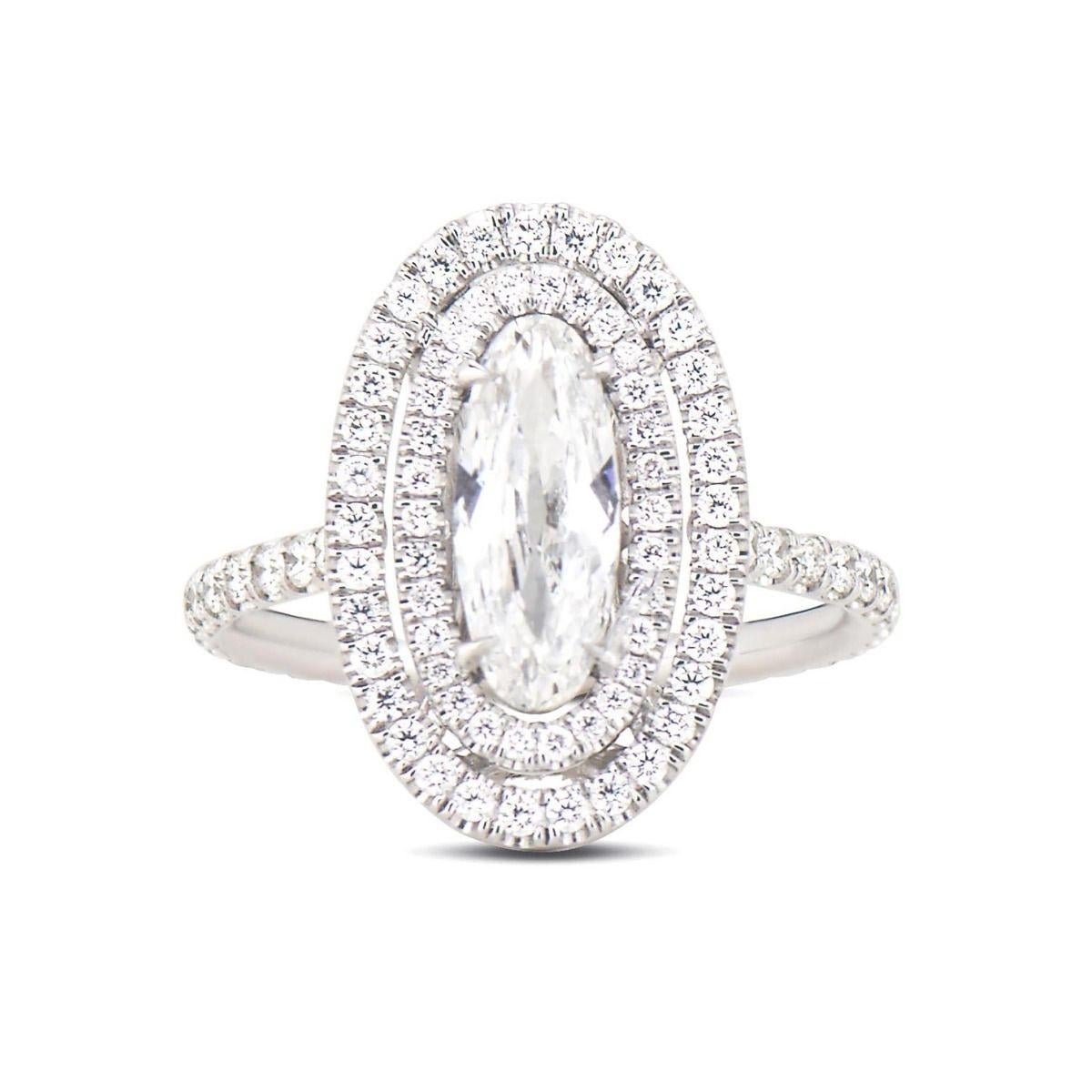 A graceful representation, this diamond and platinum hand-made engagement ring features a rare early 20th century moval-shaped diamond, weighing 0.94 ct. It is further detailed by an elegant double halo, a studded band, and a structured