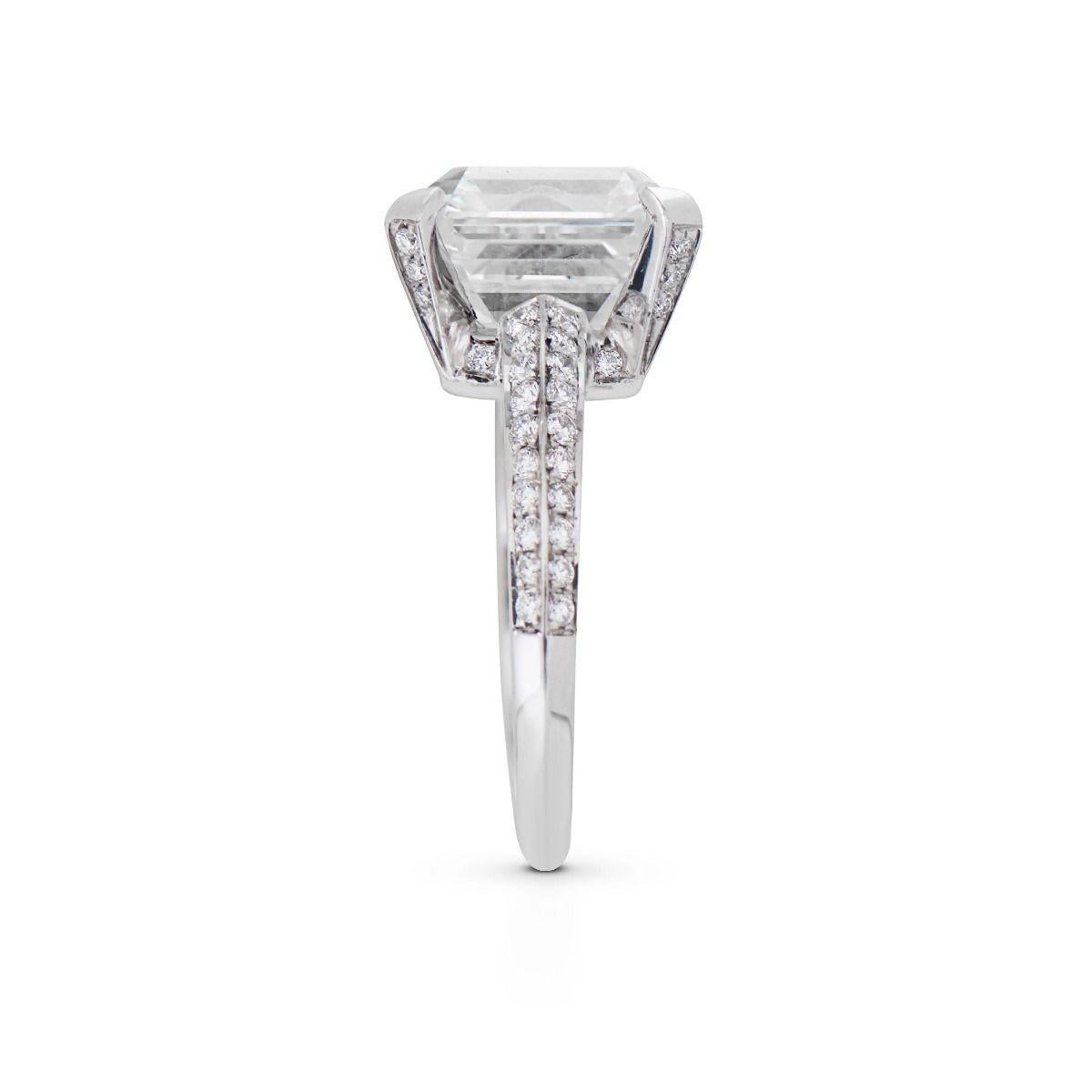 A contemporary tribute to classism, this platinum engagement ring features a prominent square emerald-cut diamond of 6.27 cts. Architectural prongs accord with its high crowning angles, while 62 round-cut diamonds, of 0.45 ct, contour the graceful,