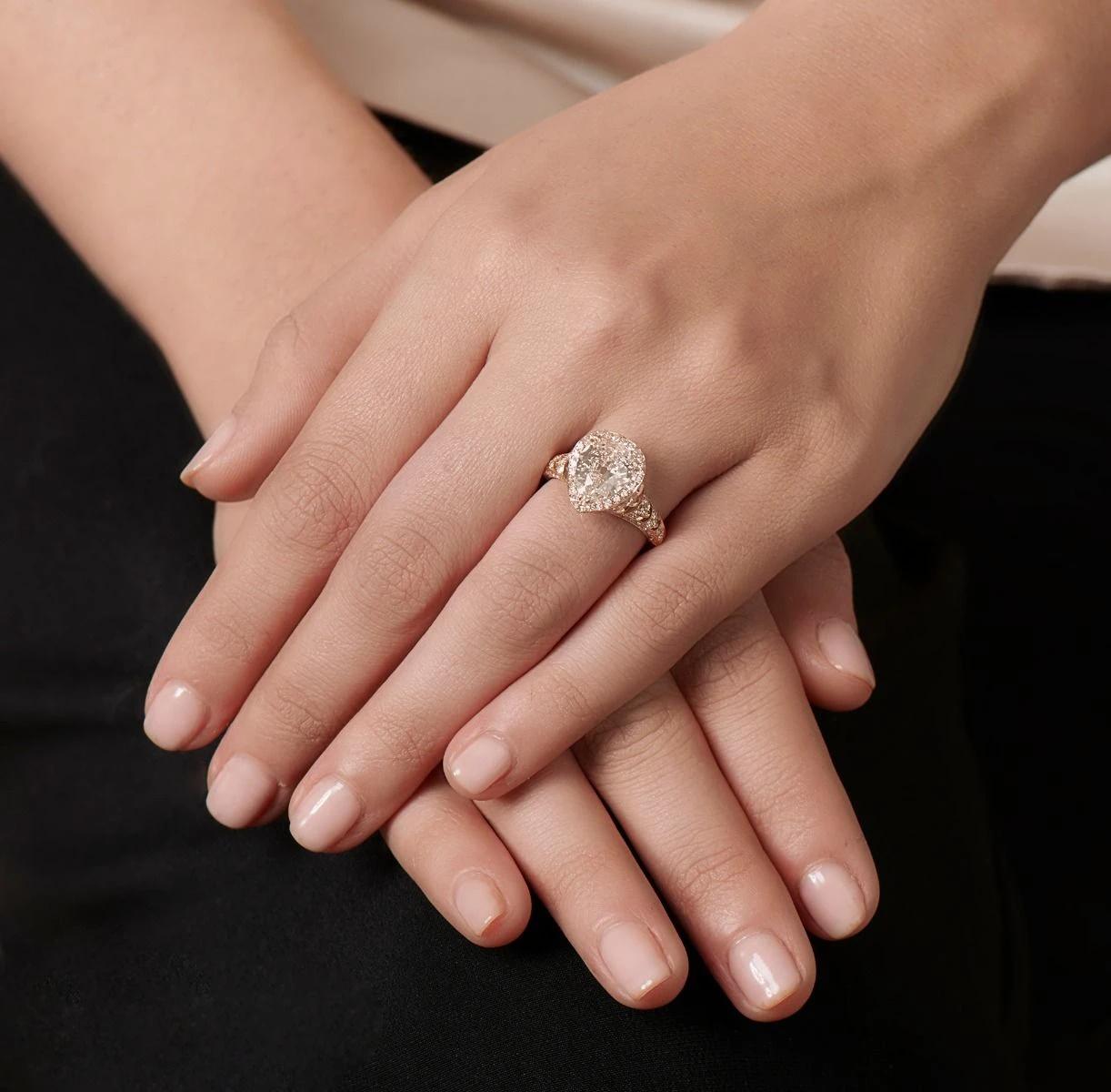 A luxurious composition, this 18K rose gold ring is hand engraved with graceful scalloped gallery pattern, centering upon an early 20th century pear-shaped diamond, weighing 2.11 cts. Further embellished with 109 round cut diamonds weighing 1.33