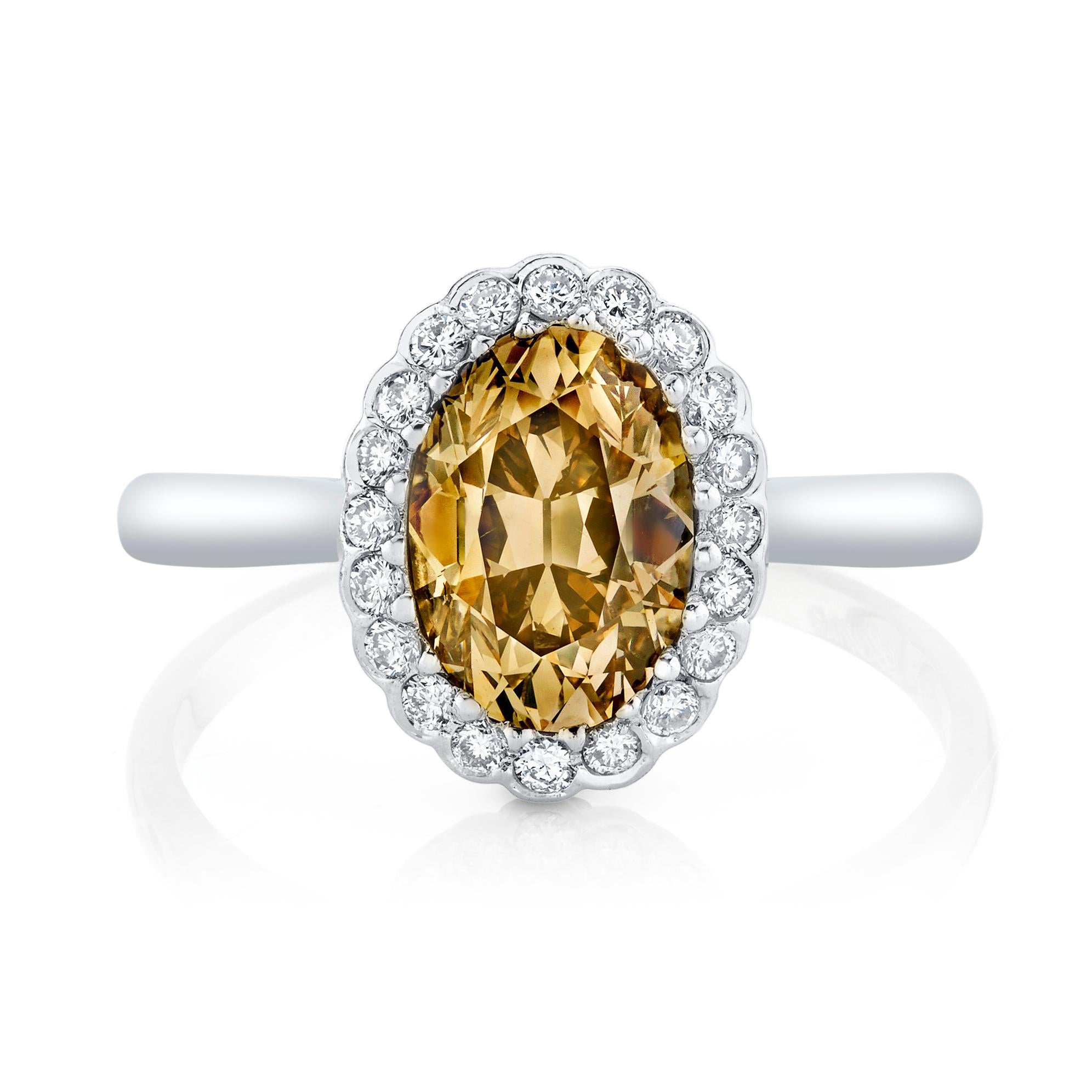 This lovely oval brilliant-cut diamond weighs 1.54 cts., displaying the warm glow of a Natural Fancy Brownish Yellowish Orange color, an elegant border of twenty-two round-cut diamonds complete the ring.

Designed and signed Neil Lane