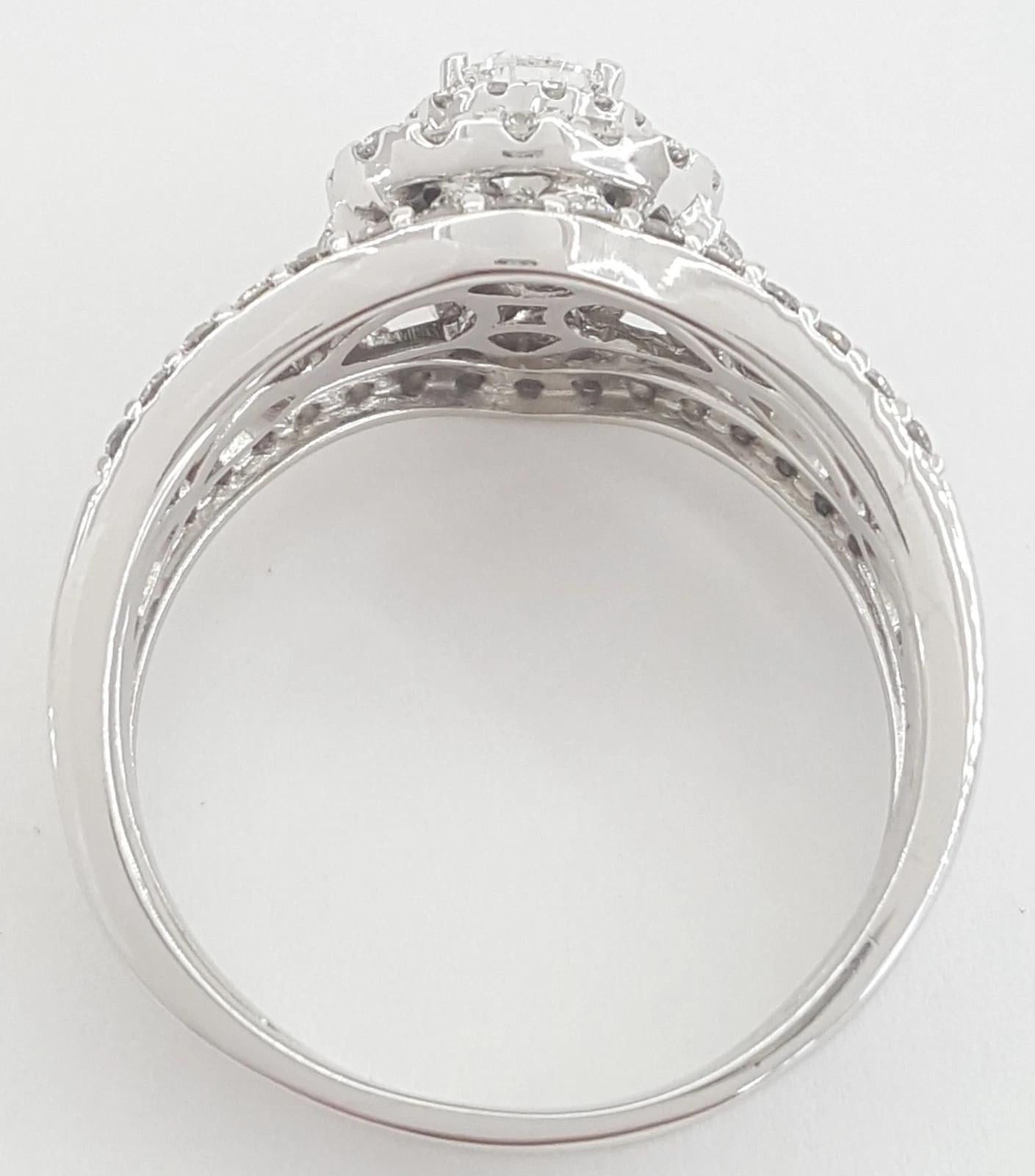 Un precioso conjunto de novia de Neil Lane con un diamante de talla pera brillante en el centro, de aproximadamente 0,55 quilates, de color H y claridad SI2. La piedra central está enmarcada por un llamativo halo doble y engastada en un elegante
