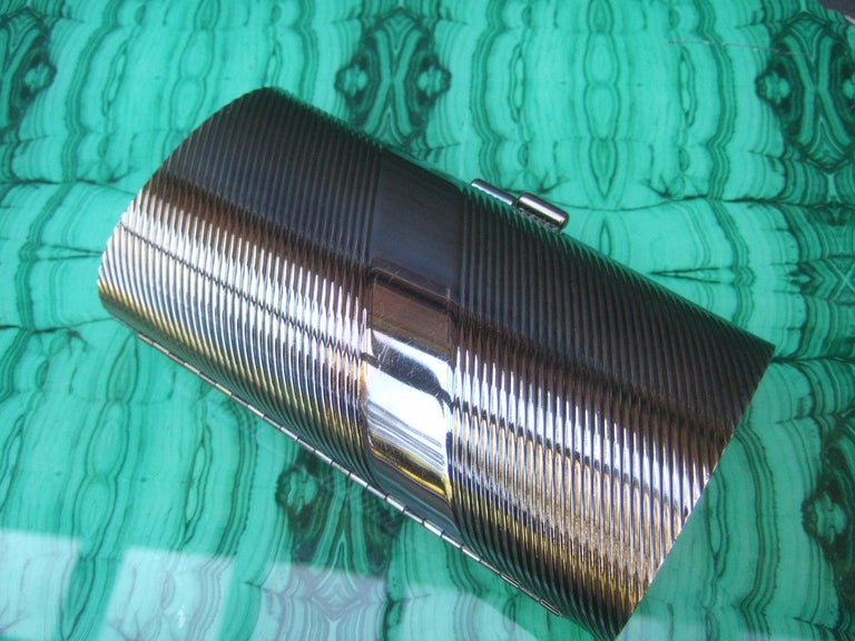 Neiman Marcus burnished silver minaudiere evening bag c 1980s

The sleek evening bag has an intentional darkened silver metal patina. Designed with grooved vertical bands on a diagonal slant. In contrast, designed with a smooth polished diagonal