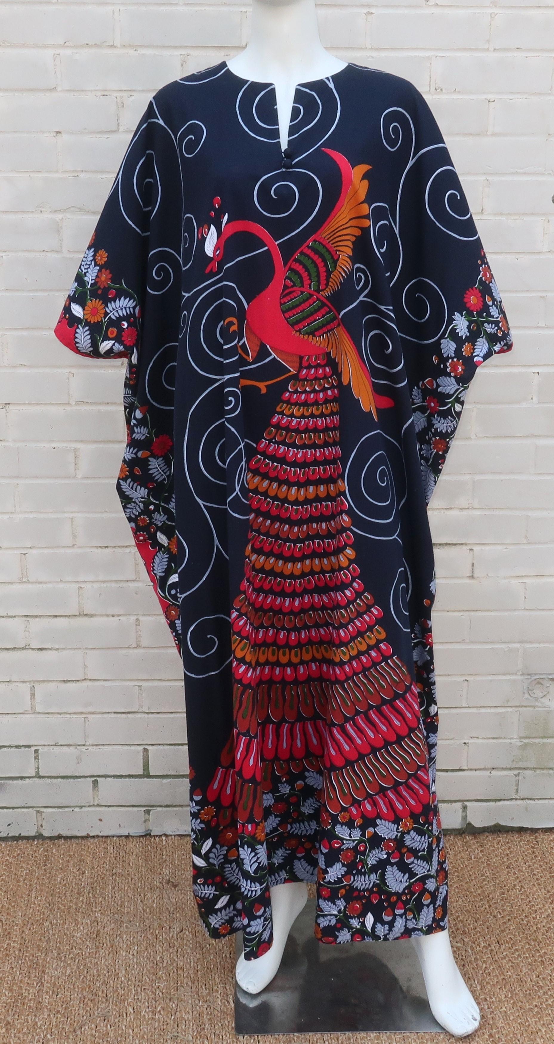 C.1980 cotton caftan lounger dress with an exotic peacock print in shades of red, cognac brown, gray and green with touches of white highlights and a near black background.  The pullover construction has a collarless neckline and two fabric covered