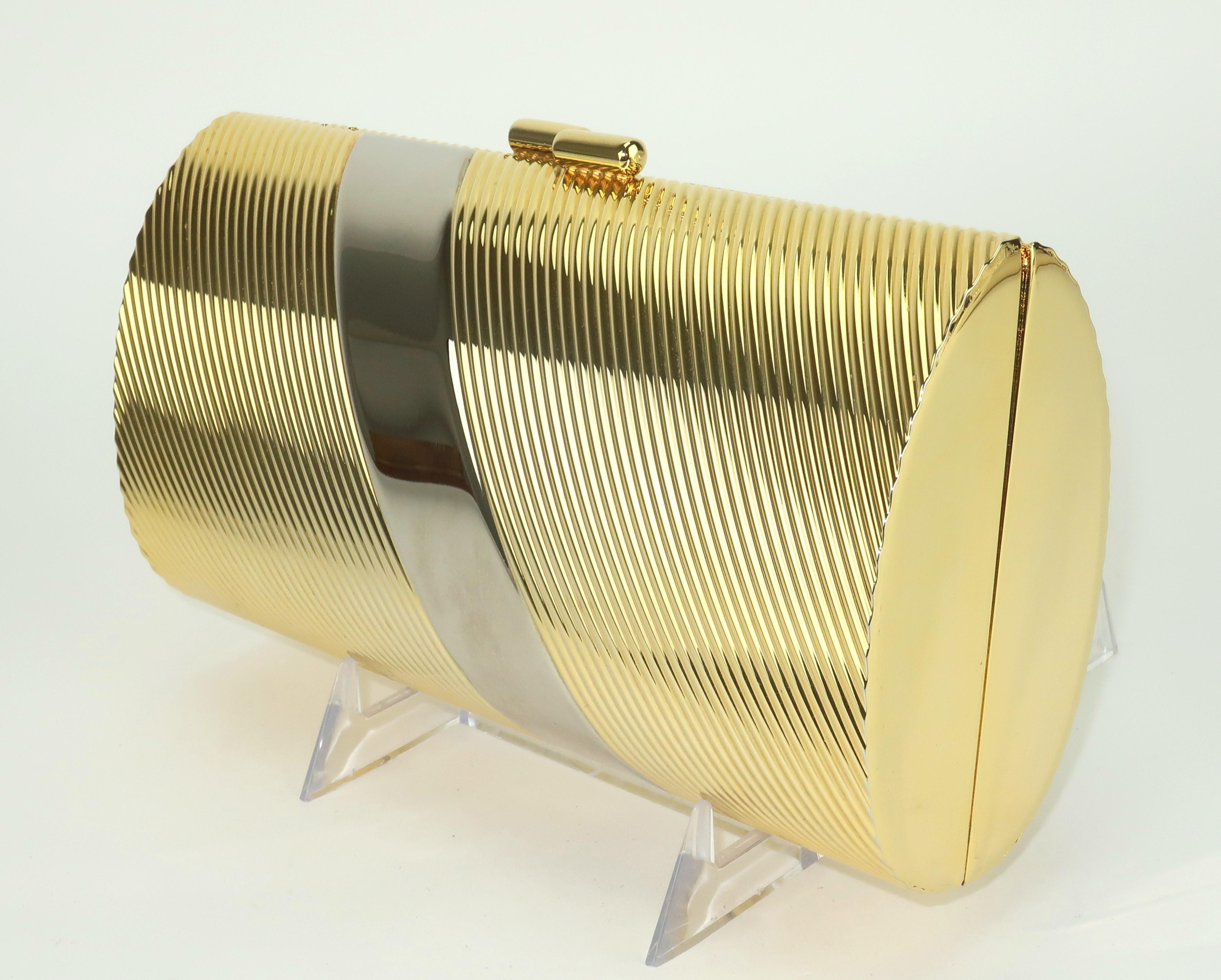This 1980's Neiman Marcus handbag is a precious bauble, as fun to display as it is to carry.  The gold metal cylinder shape has fluted sides and a silver band at the diagonal for a stylish touch.  The jewelry-like braided chain shoulder strap is