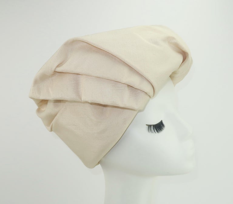 C.1960 Neiman Marcus 'Made to Order' silk shantung hat in an ivory or candlelight white shade.  The hat has a chic turban style design with effortless folds that create a stylish topper.  It takes on a casual look when worn backwards as shown in