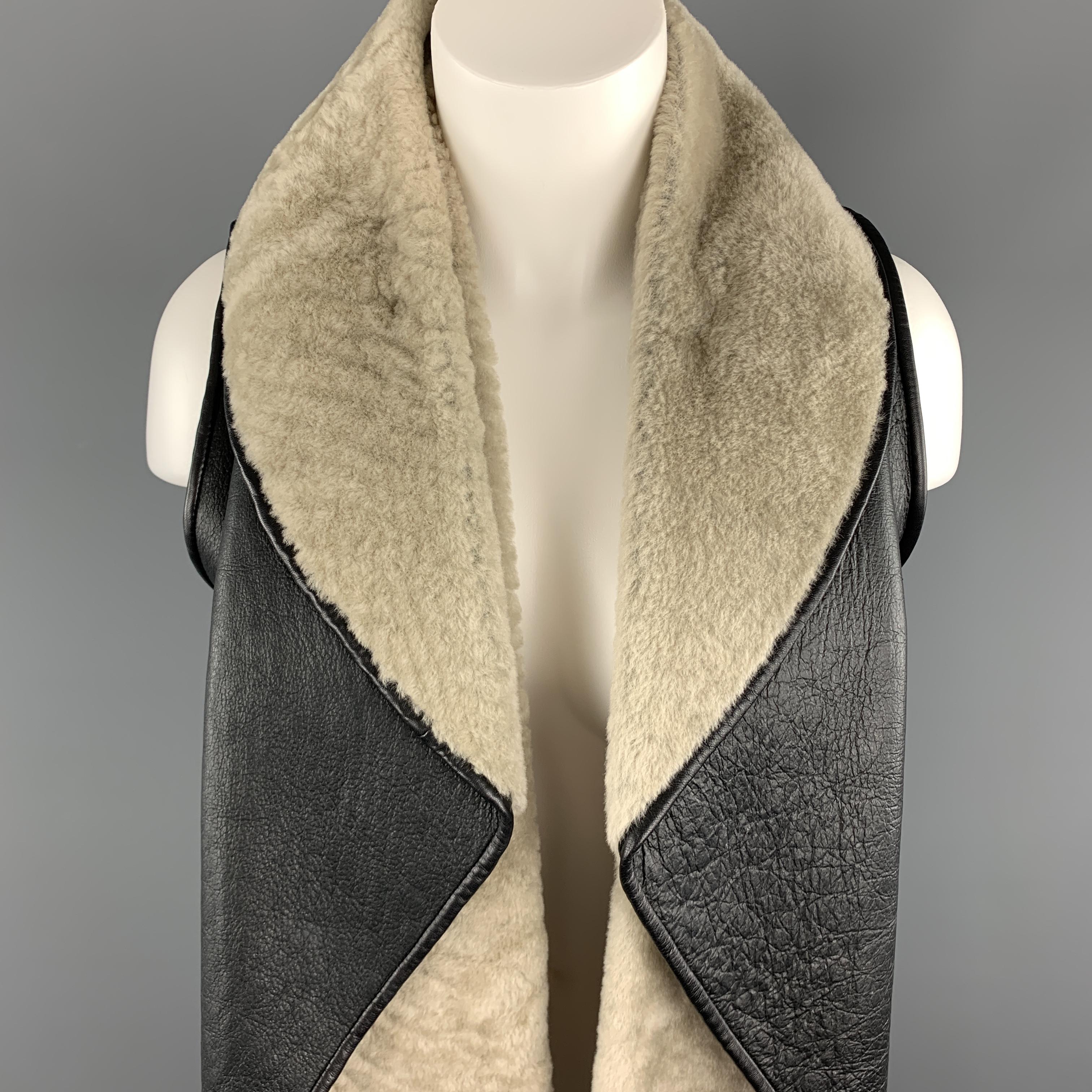 NELLIE PARTOW vest comes in black shearling with muted gray beige trimmed fur with a round folded draped lapel collar. Made in USA.

Excellent Pre-Owned Condition.
Marked:  XS

Measurements:

Shoulder: 13 in.
Bust: 34 in.
Length: 23-28 in.