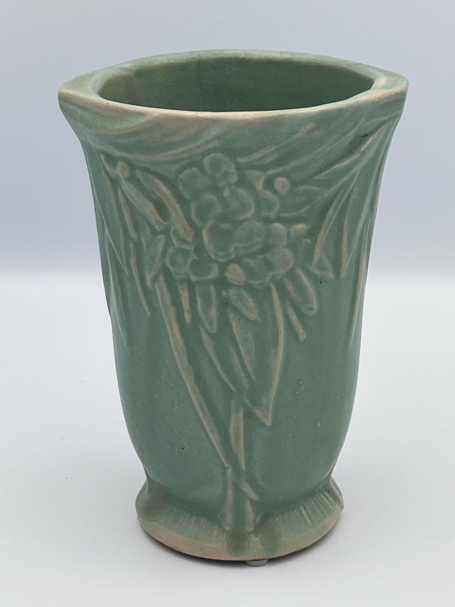 Questo squisito vaso Nelson McCoy dei primi anni '20 presenta l'amato disegno Greene & Greene, un segno distintivo della prima arte dell'azienda. Il pezzo è graziosamente ornato da un motivo in rilievo di foglie e bacche intrecciate, che gli