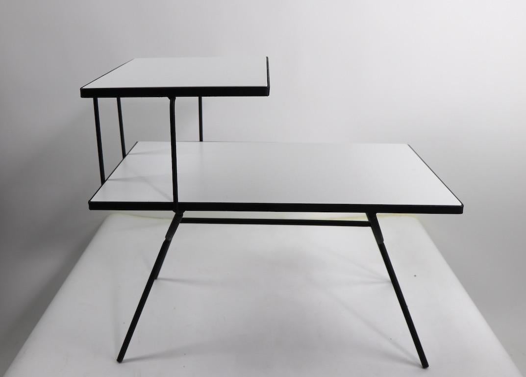 Architectural design wrought iron step end table by Frank and Sons for Arbuck, after George Nelson.
Unusual white table surfaces create a dramatic and graphic effect. The wrought iron frame has been newly spray painted black, clean ready to use